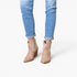 A person wearing light blue cuffed jeans and beige western-style ankle boots with glittery embellished shafts, shown against a plain white studio background.