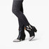 Black leather ankle boots with silver glitter pointed toes and white embroidered bat details, shown on a model wearing dark gray skinny jeans against a white studio background.