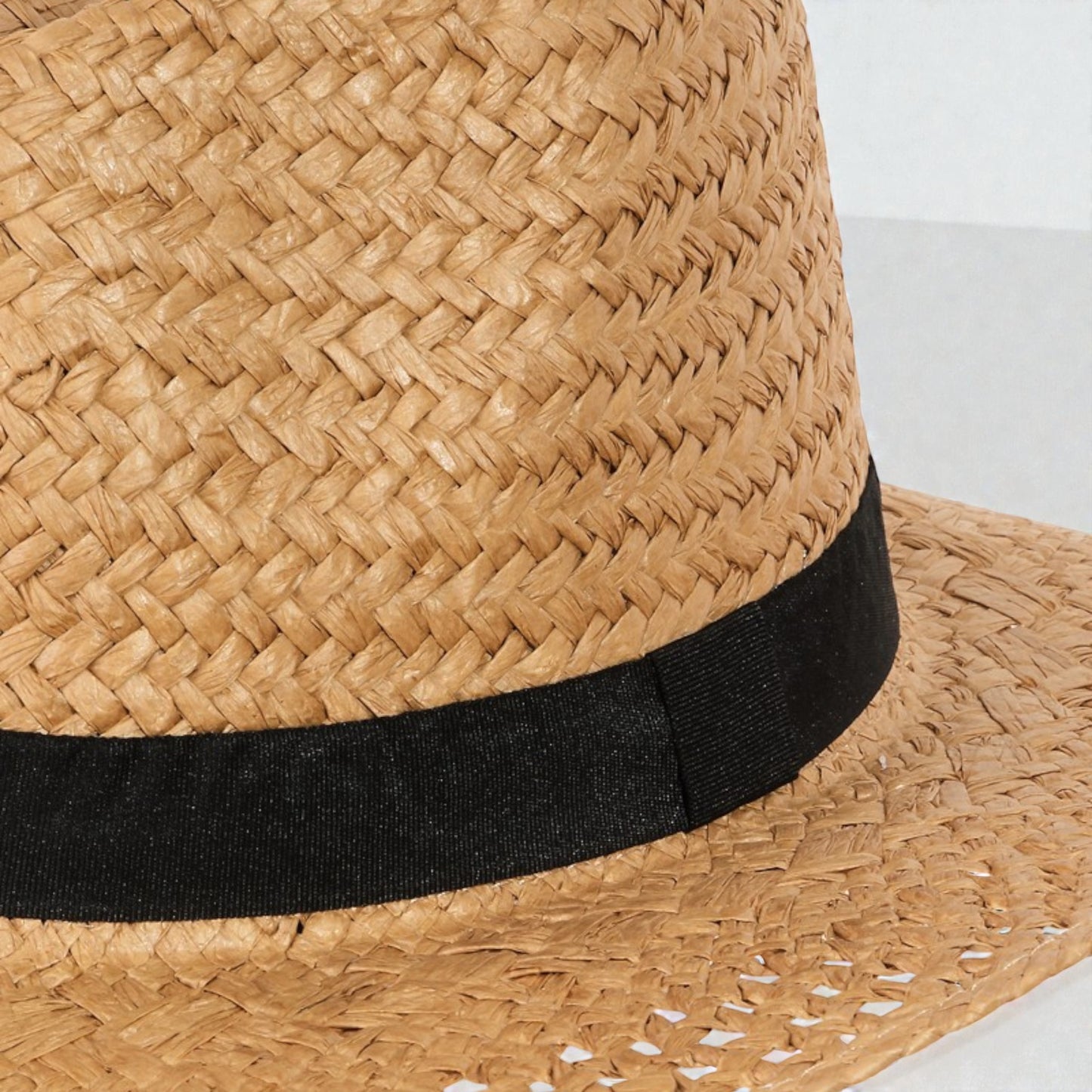 Close-up of a straw hat with a black band on a white background