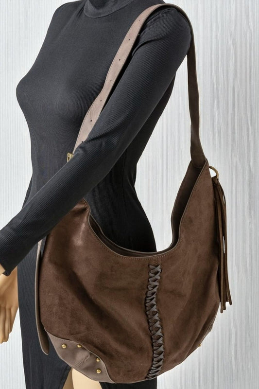 Brown suede handbag with fringe details on a plain background