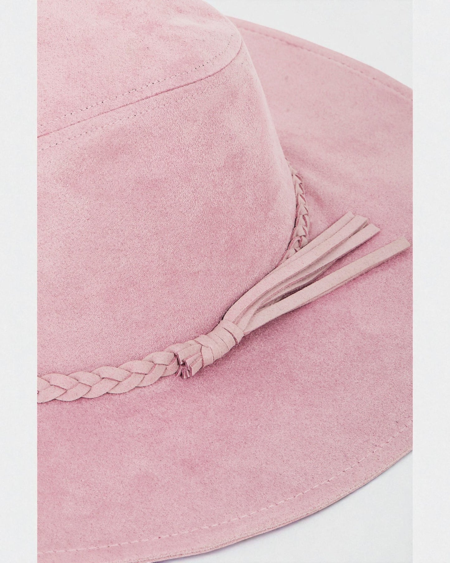 Pink bucket hat with a braided detail on a white background