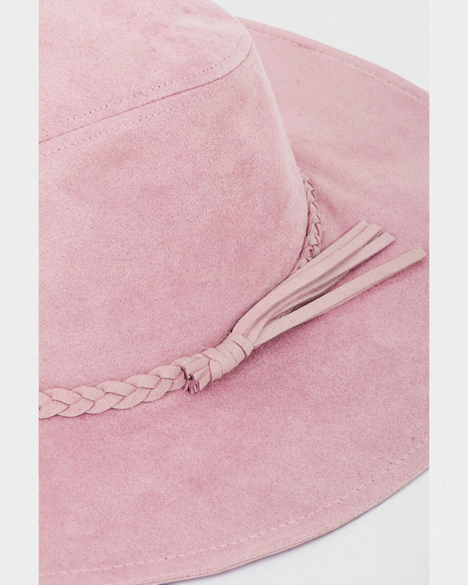 Pink bucket hat with a braided detail on a white background