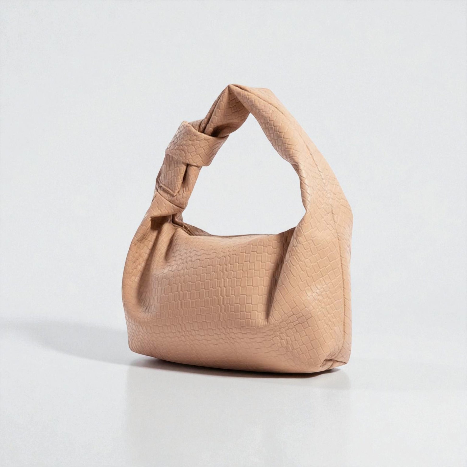 Beige handbag with a textured pattern on a light gray background