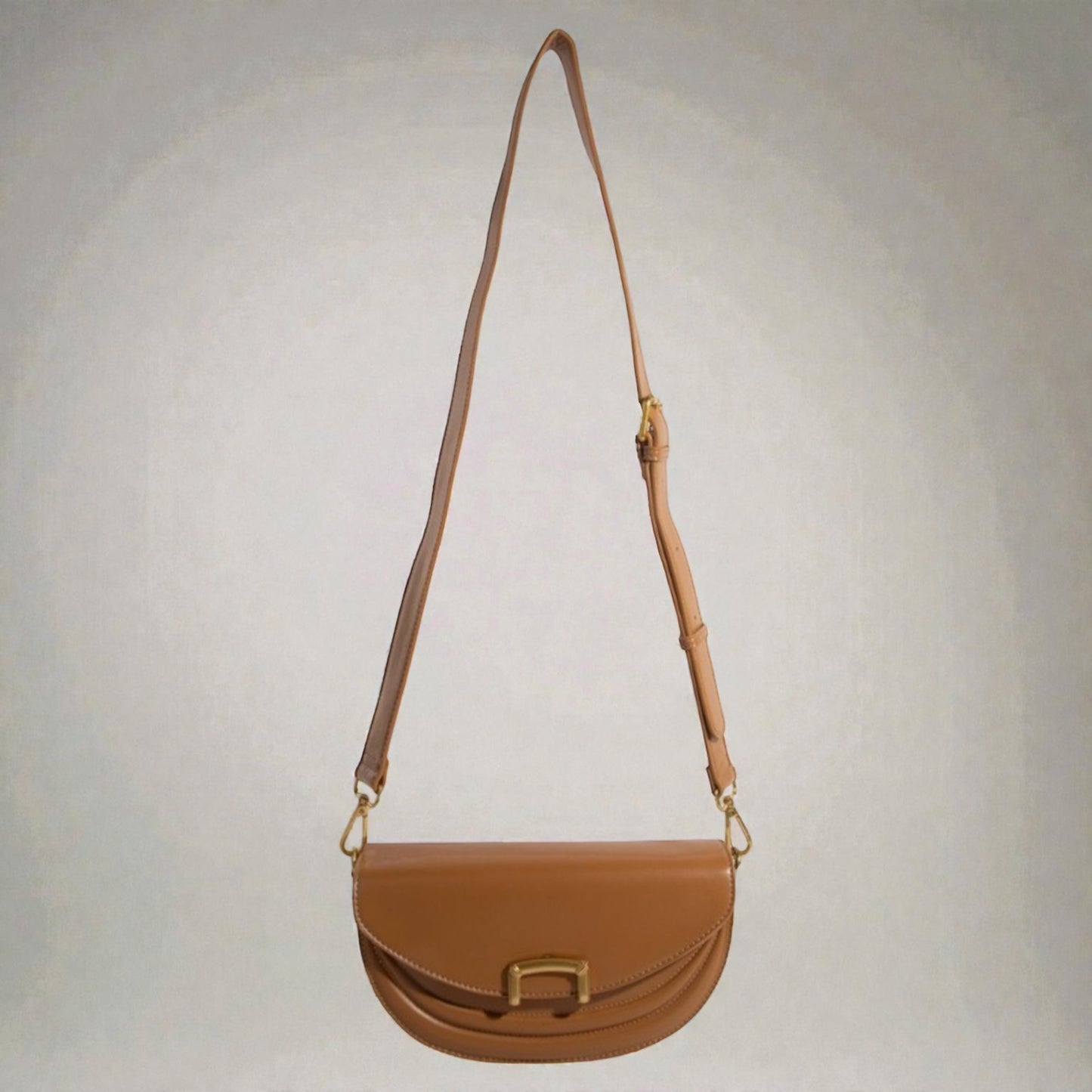 Brown leather handbag with a strap on a light gray background