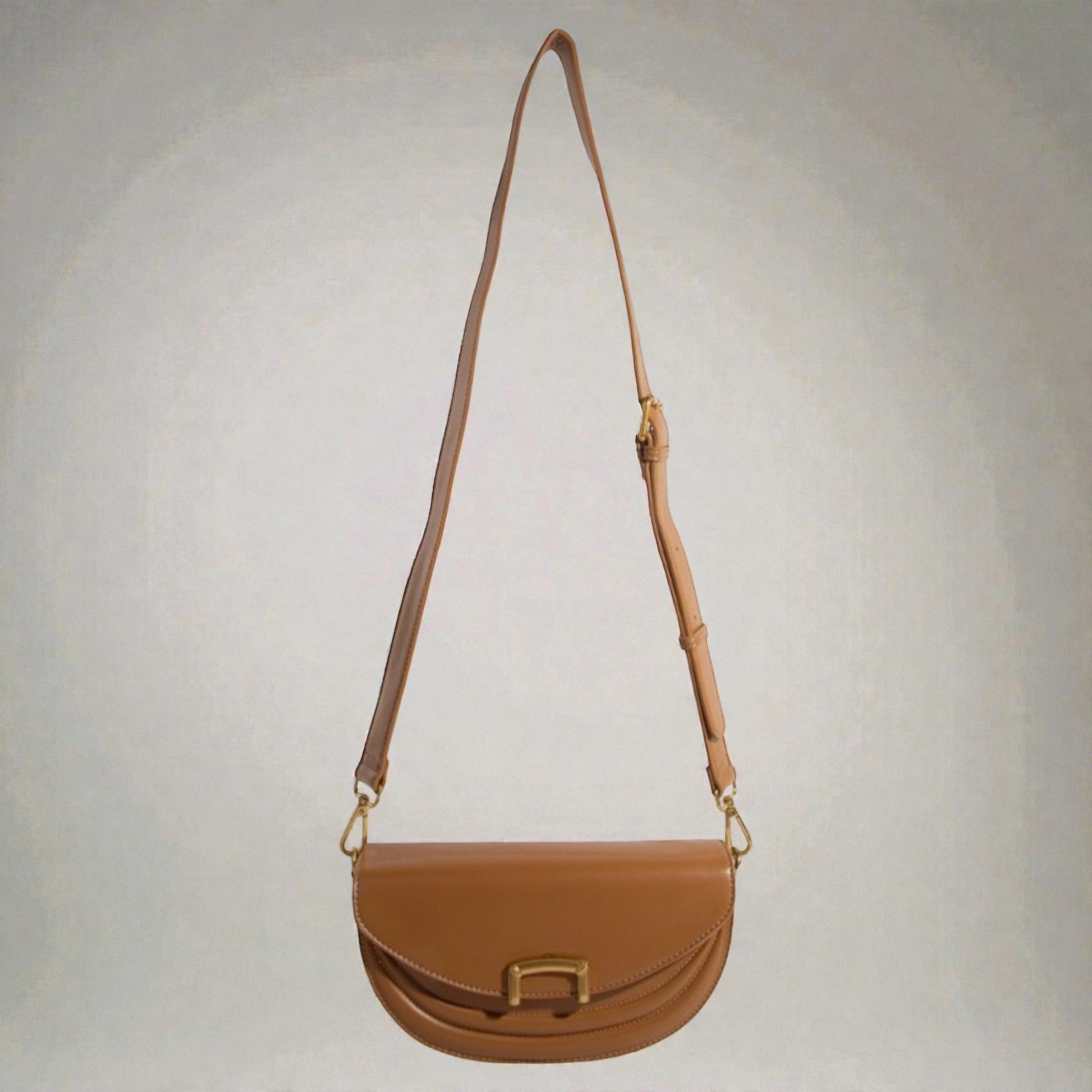 Brown leather handbag with a strap on a light gray background