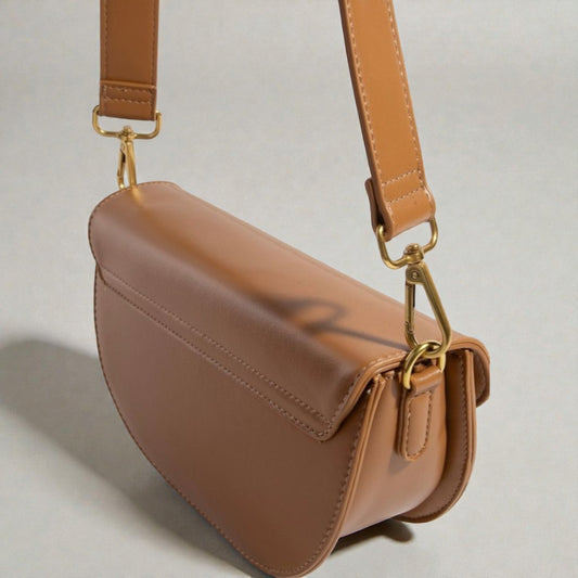 Brown leather handbag with gold hardware on a light gray background
