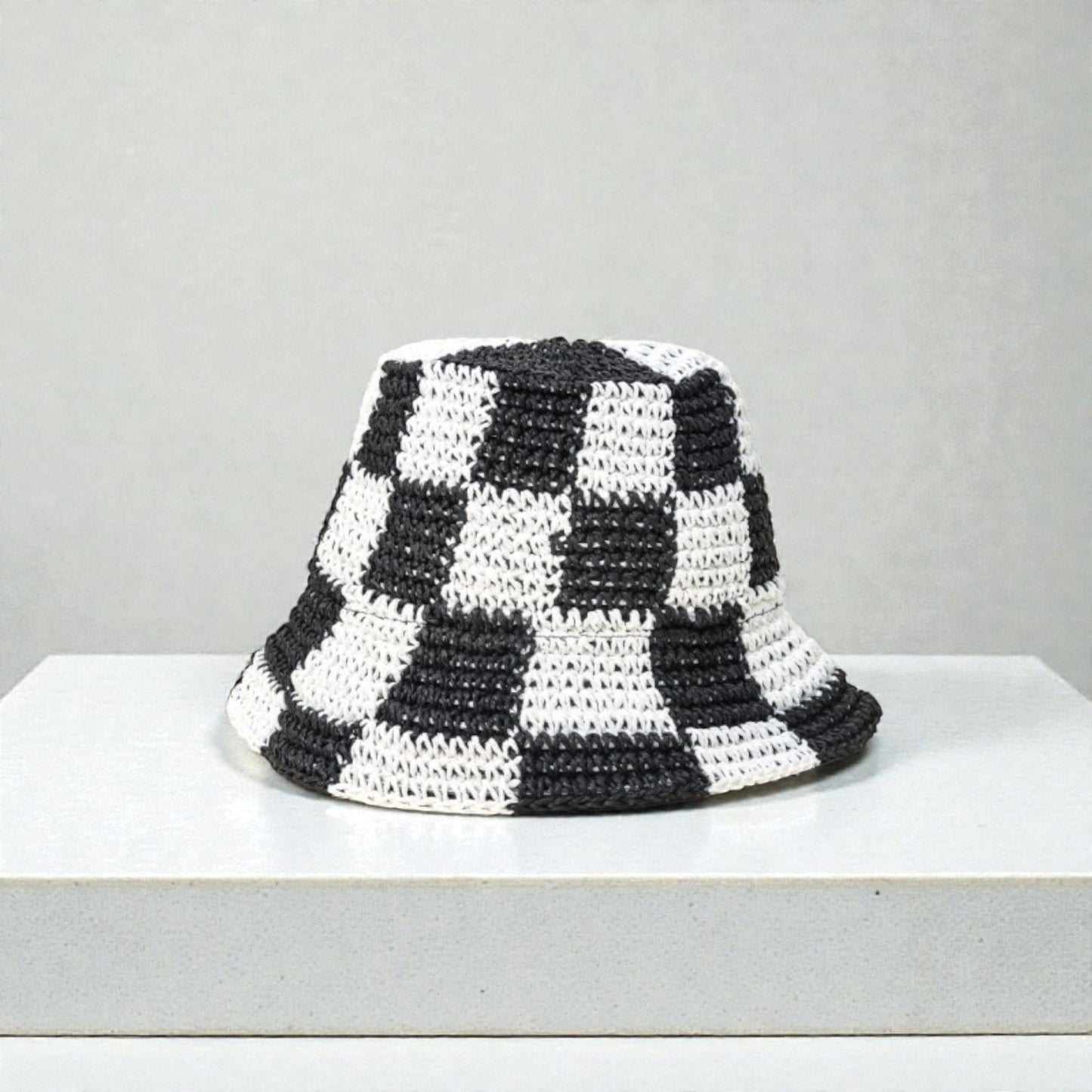 Black and white checkered bucket hat on a light gray background