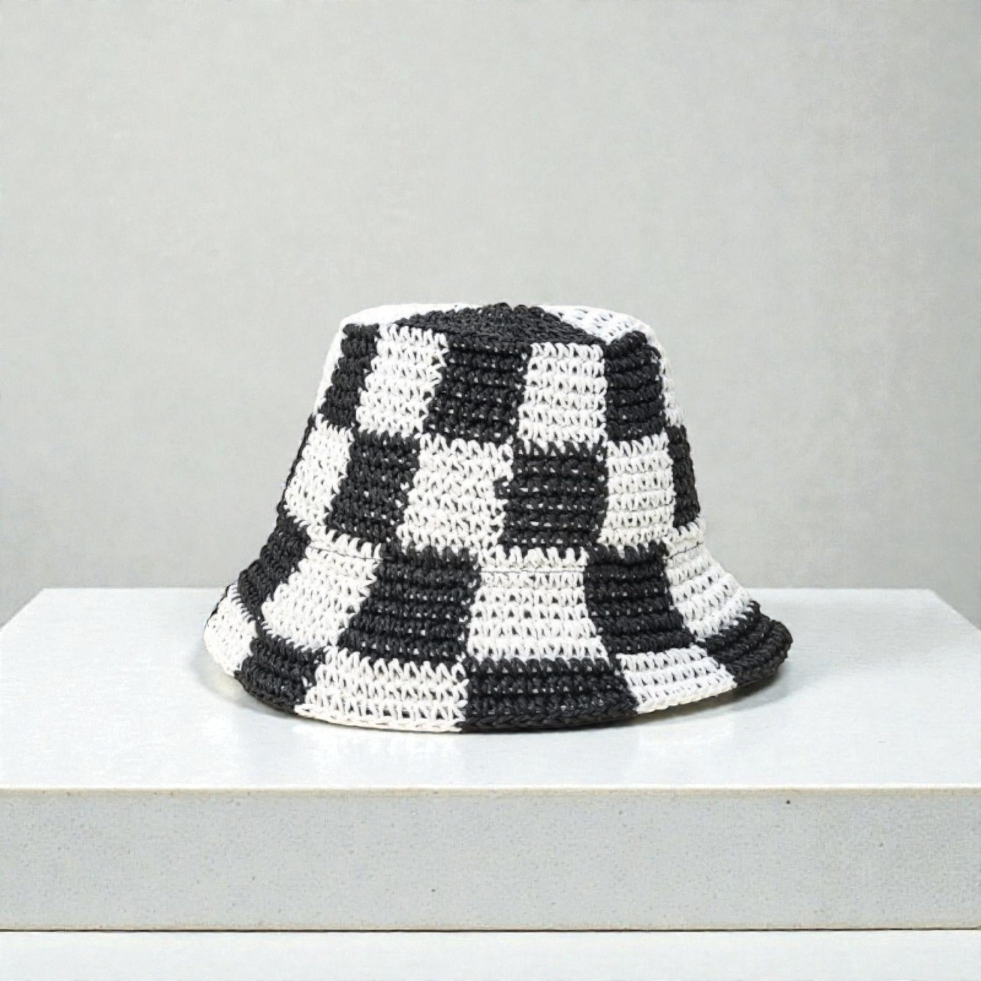 Black and white checkered bucket hat on a light gray background