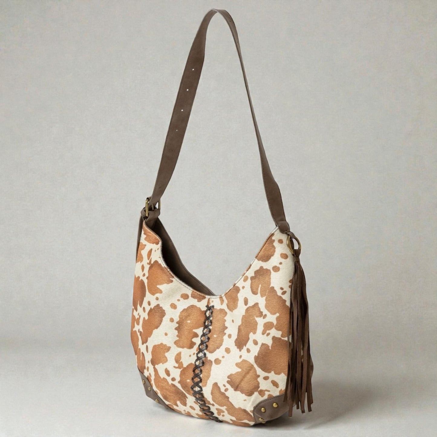 Brown and white patterned handbag with a brown strap on a light gray background