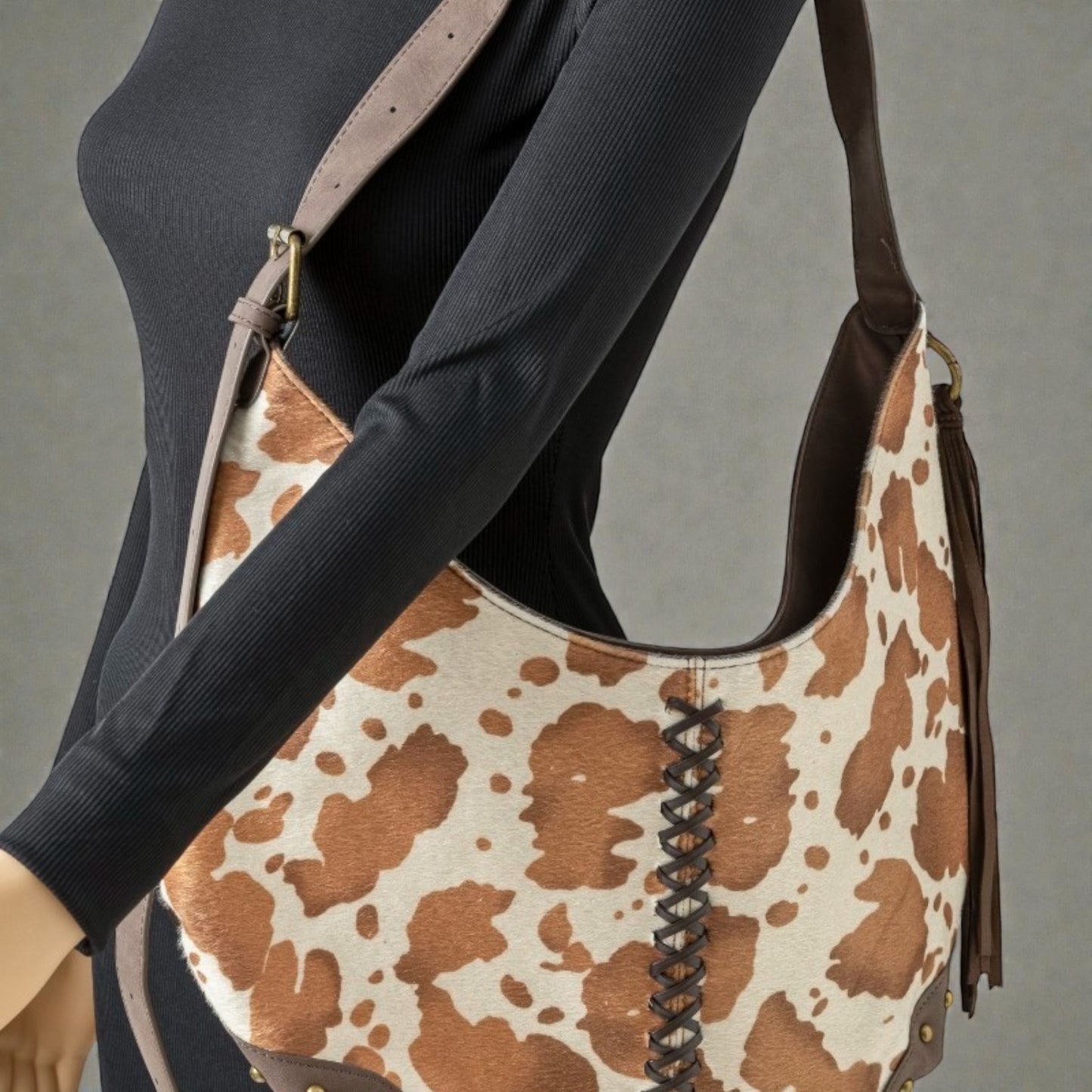 Person holding a brown and white patterned handbag with a plain background