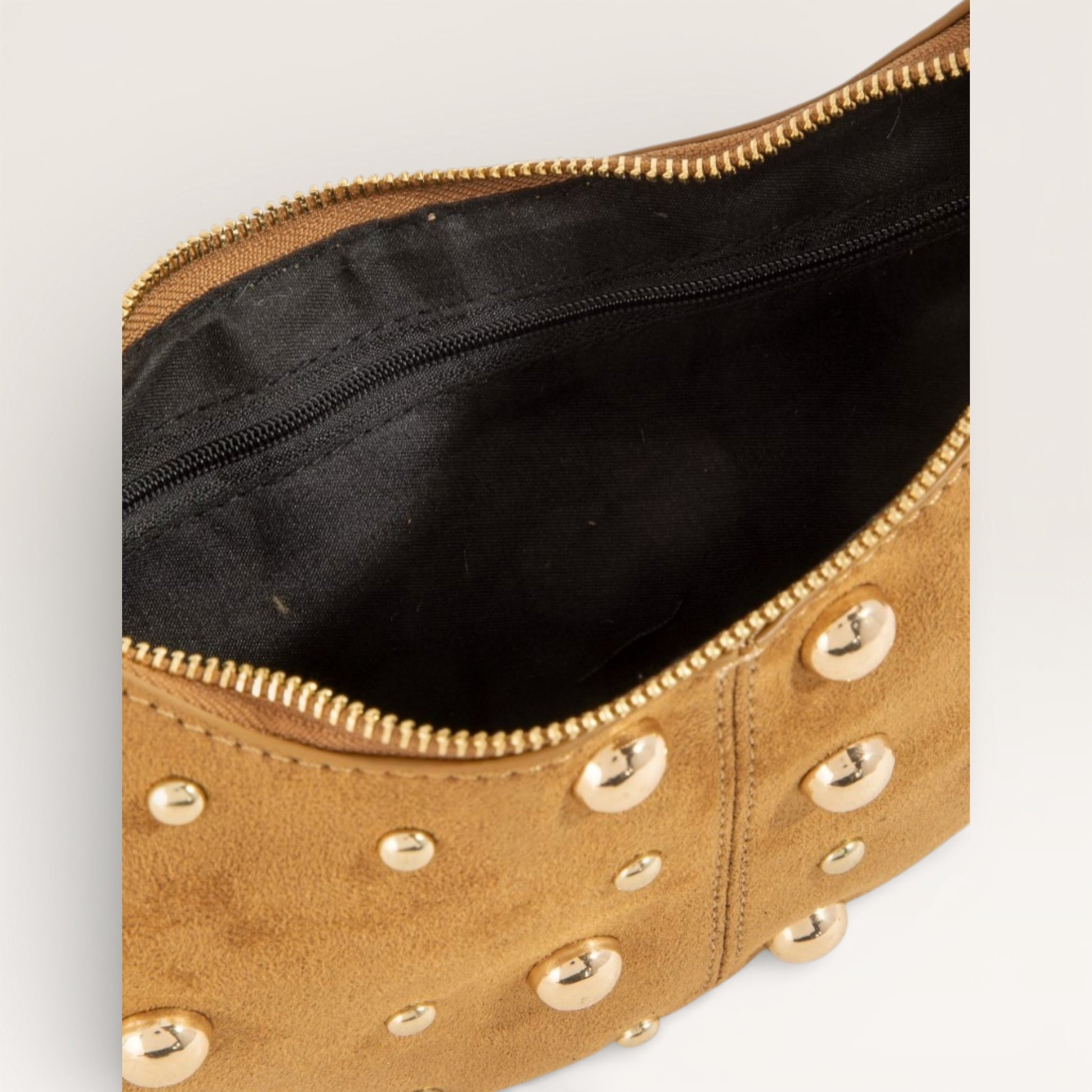 Tan clutch bag with gold studs on a light gray background