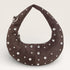 Brown handbag with silver studs on a light gray background