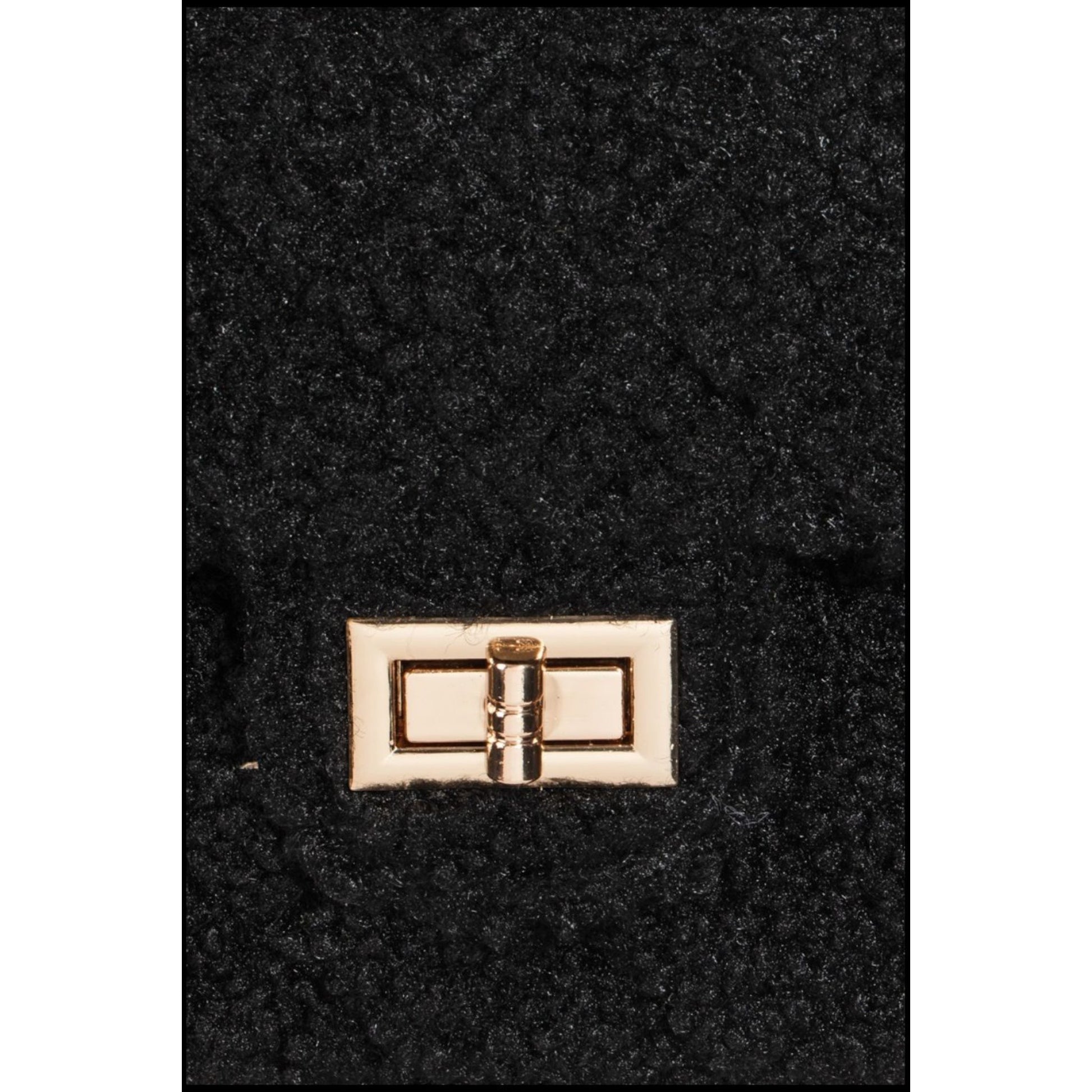 Close-up of a black textured surface with a gold buckle detail