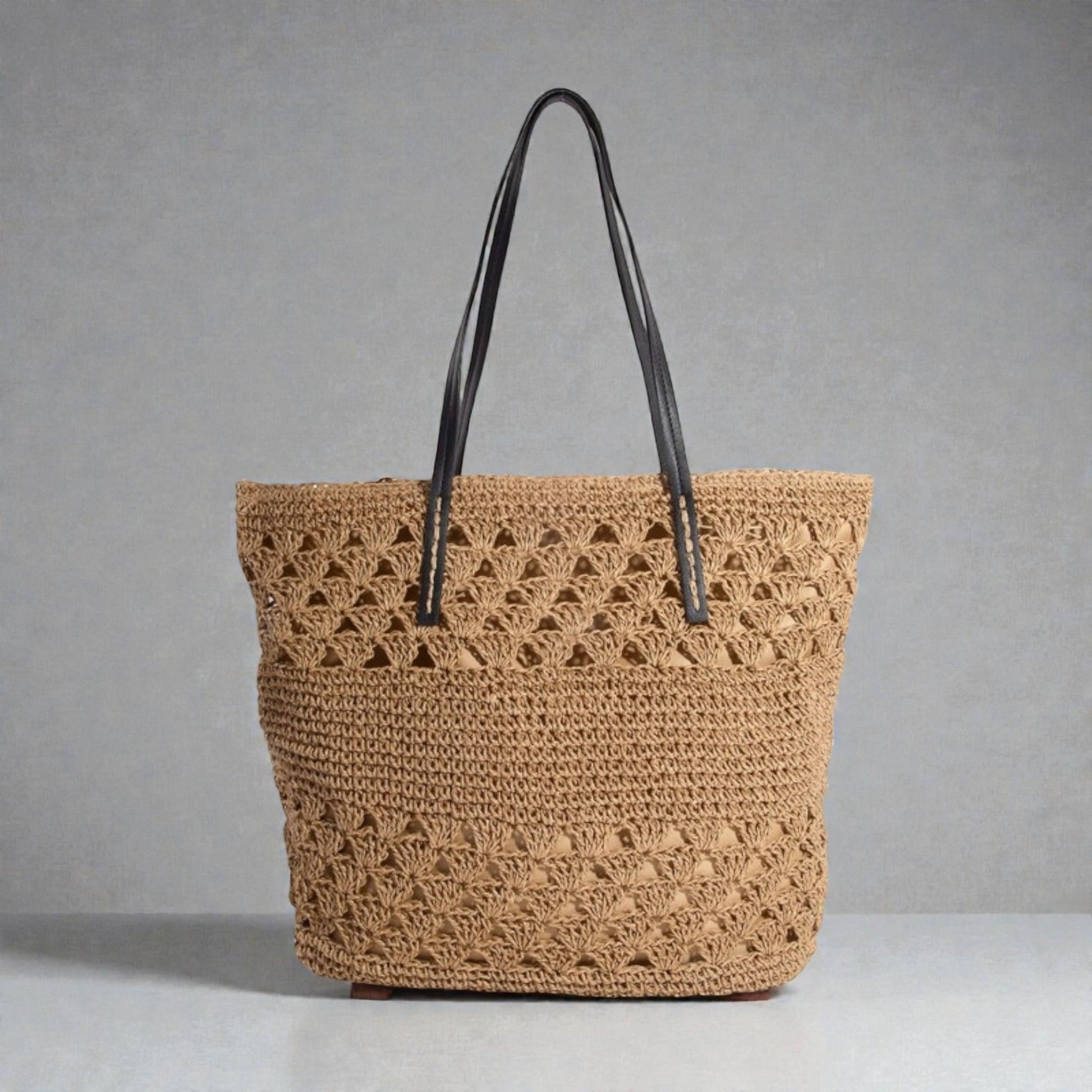 Brown woven tote bag with black handles on a gray background