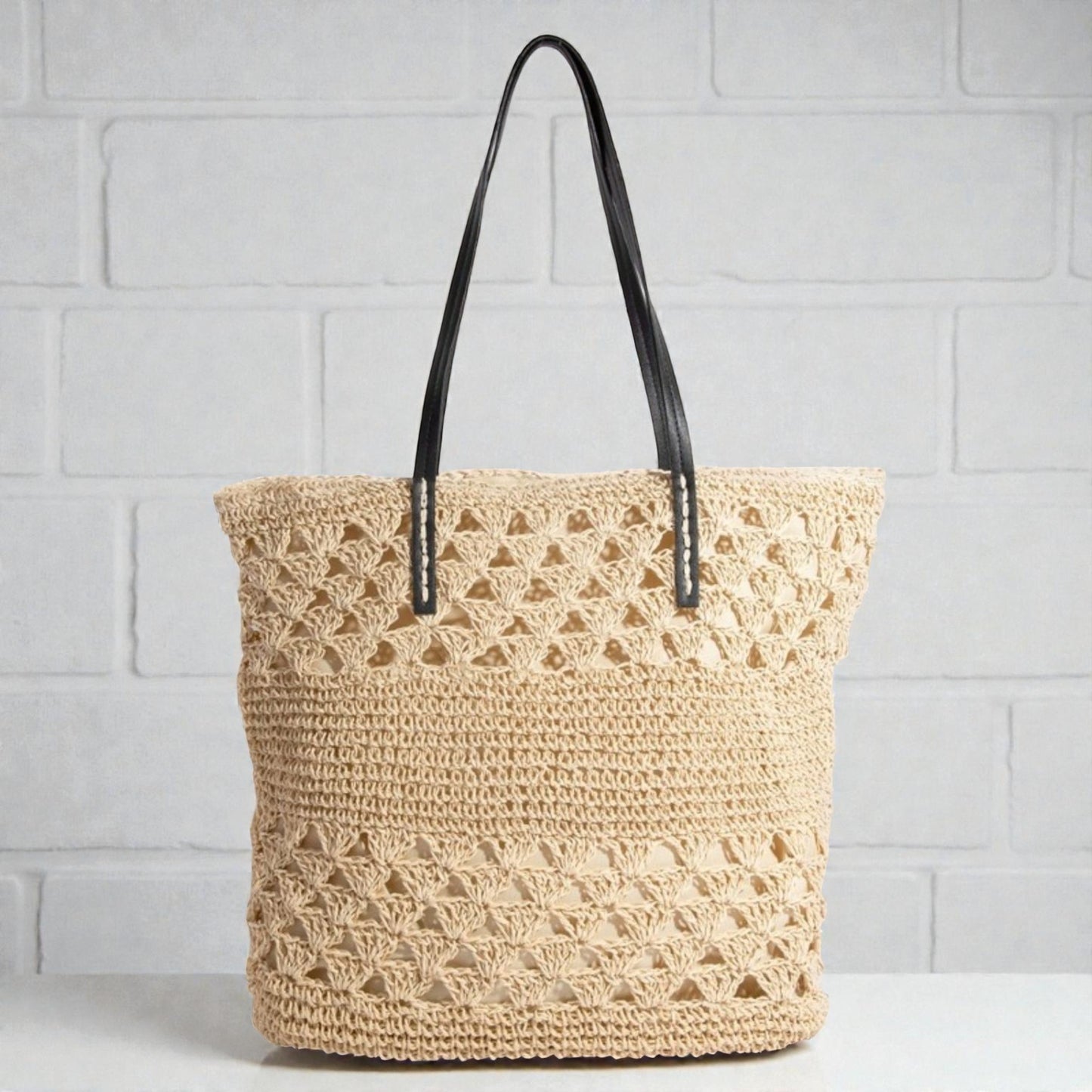 Woven tote bag with black handles on a light gray background