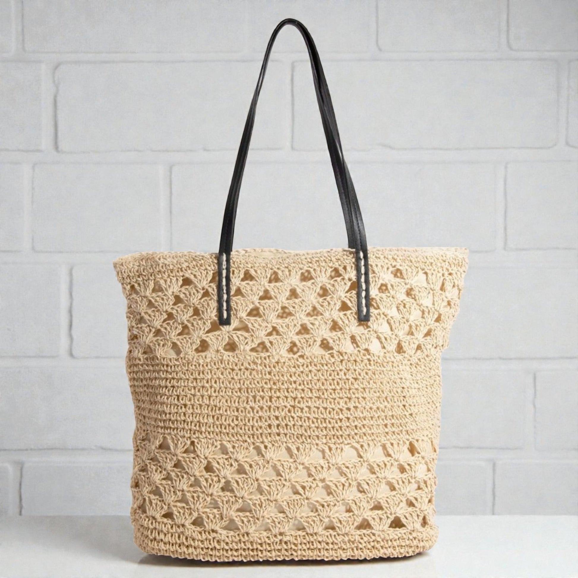 Woven tote bag with black handles on a light gray background