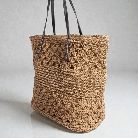 Brown crochet bag with black straps on a light gray background