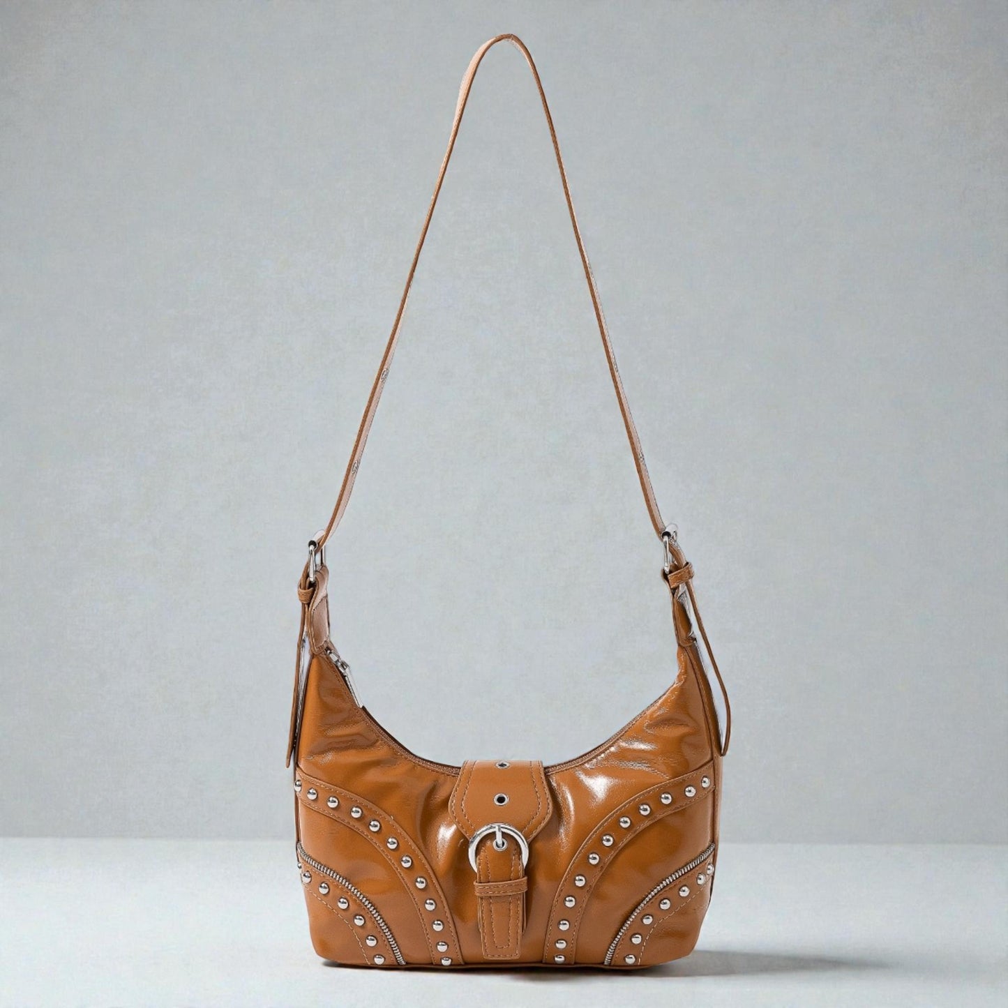 Brown leather handbag with studs on a gray background