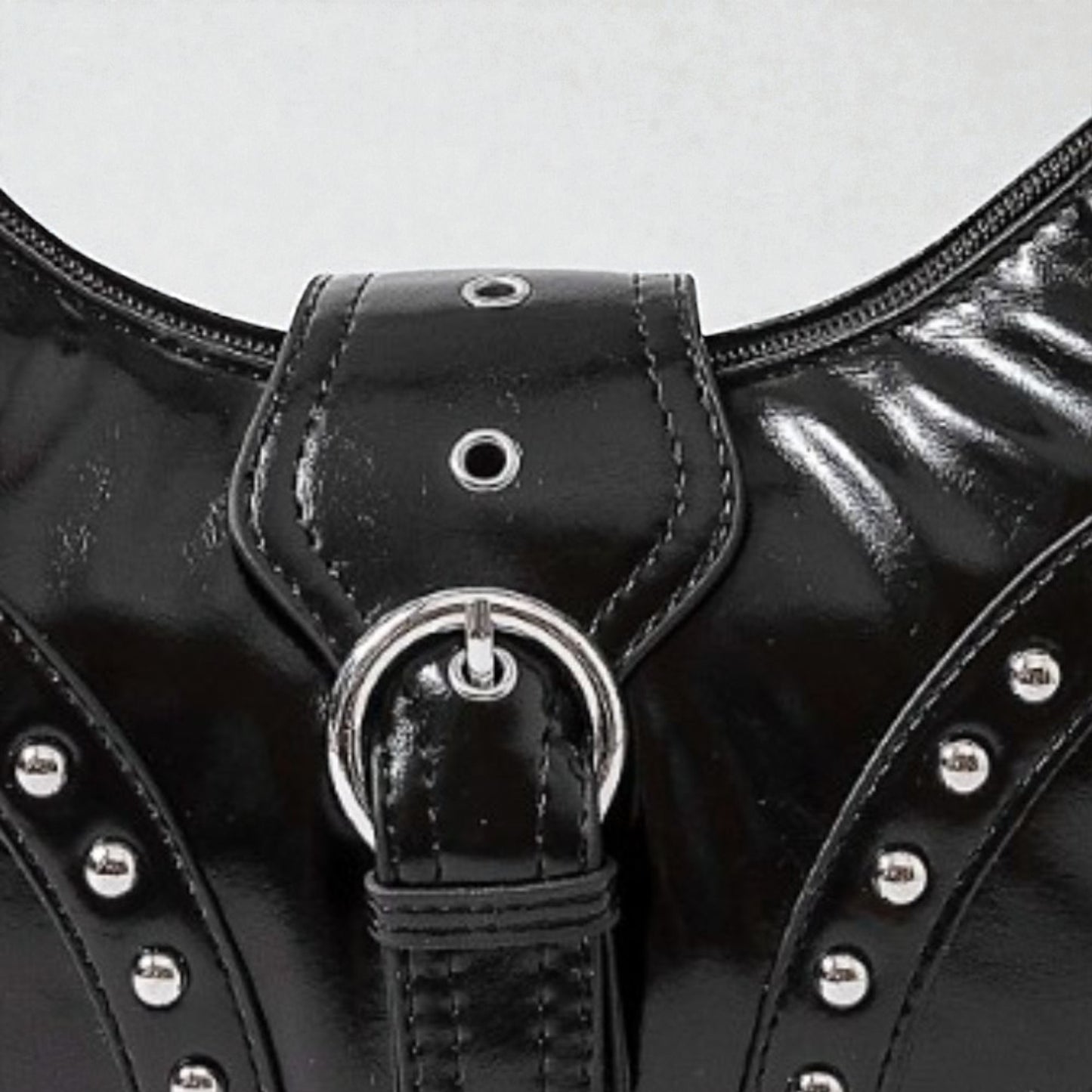 Close-up of a black leather bag with silver studs and buckle on a white background