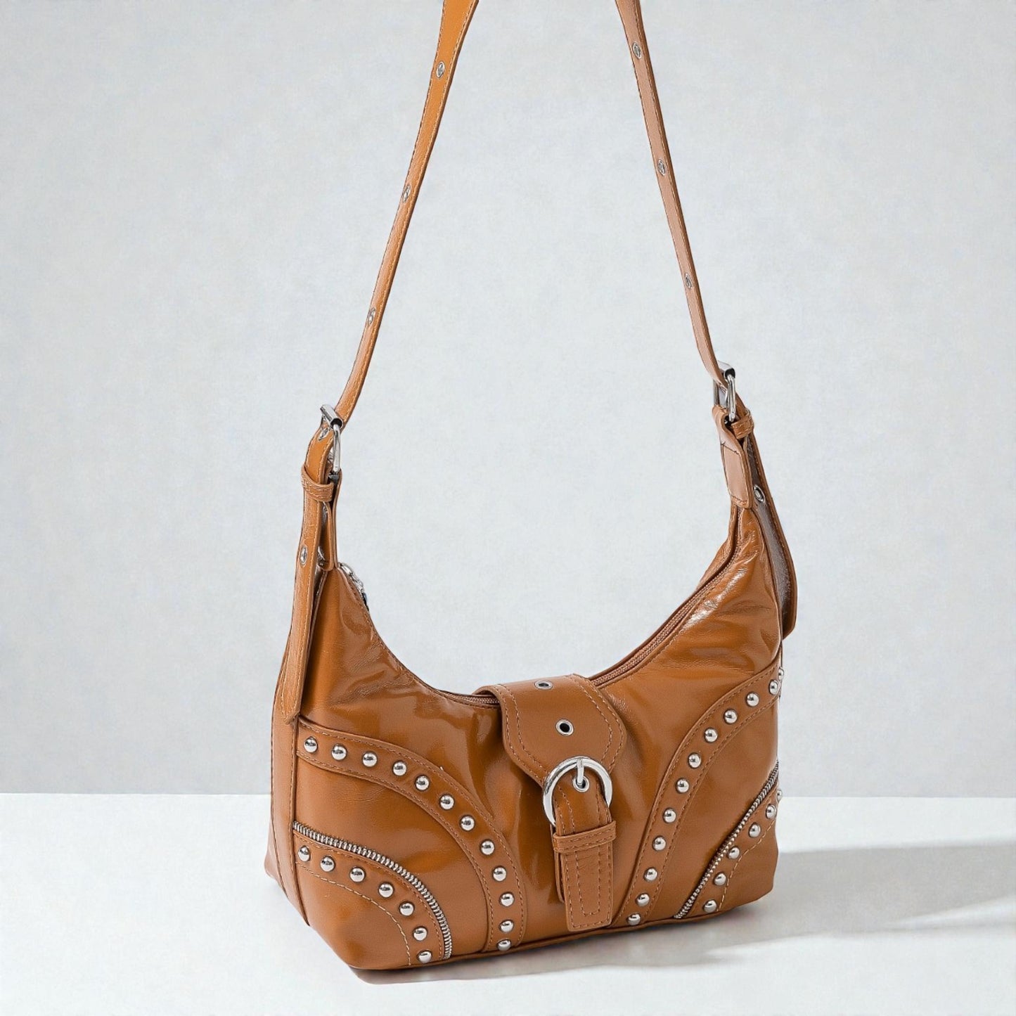 Brown leather handbag with studs on a light gray background