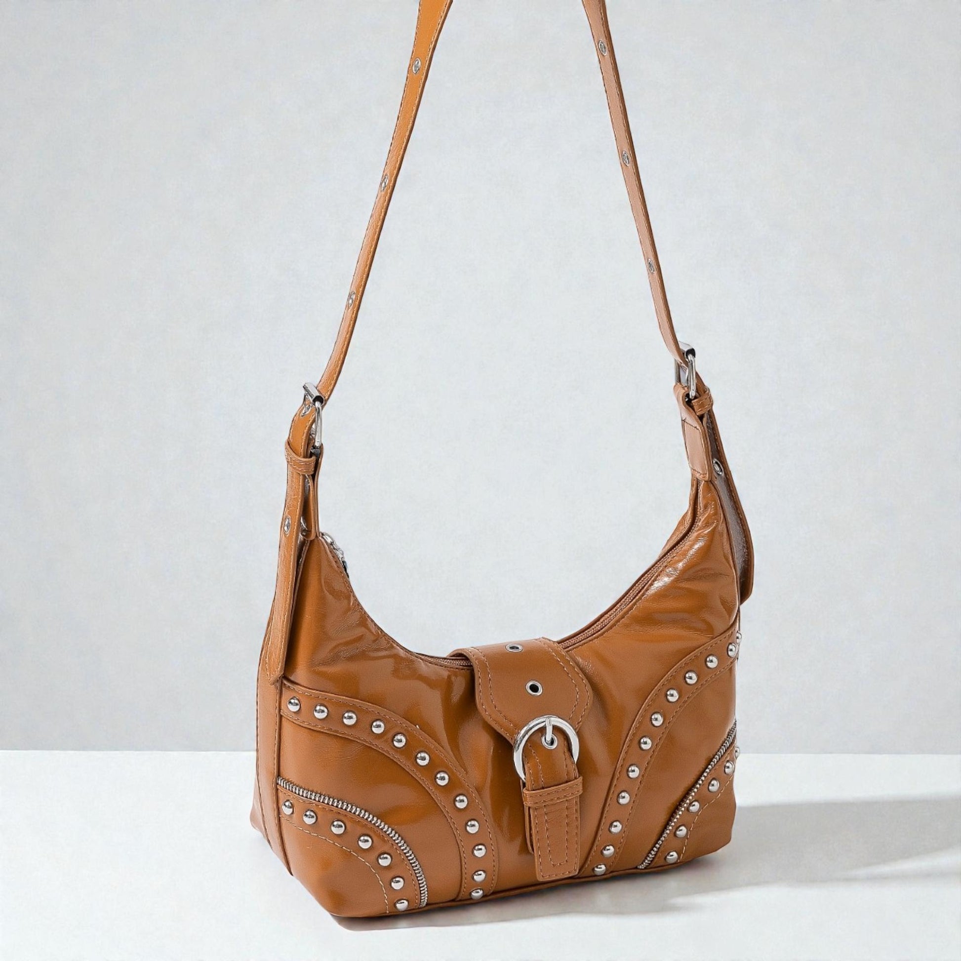 Brown leather handbag with studs on a light gray background
