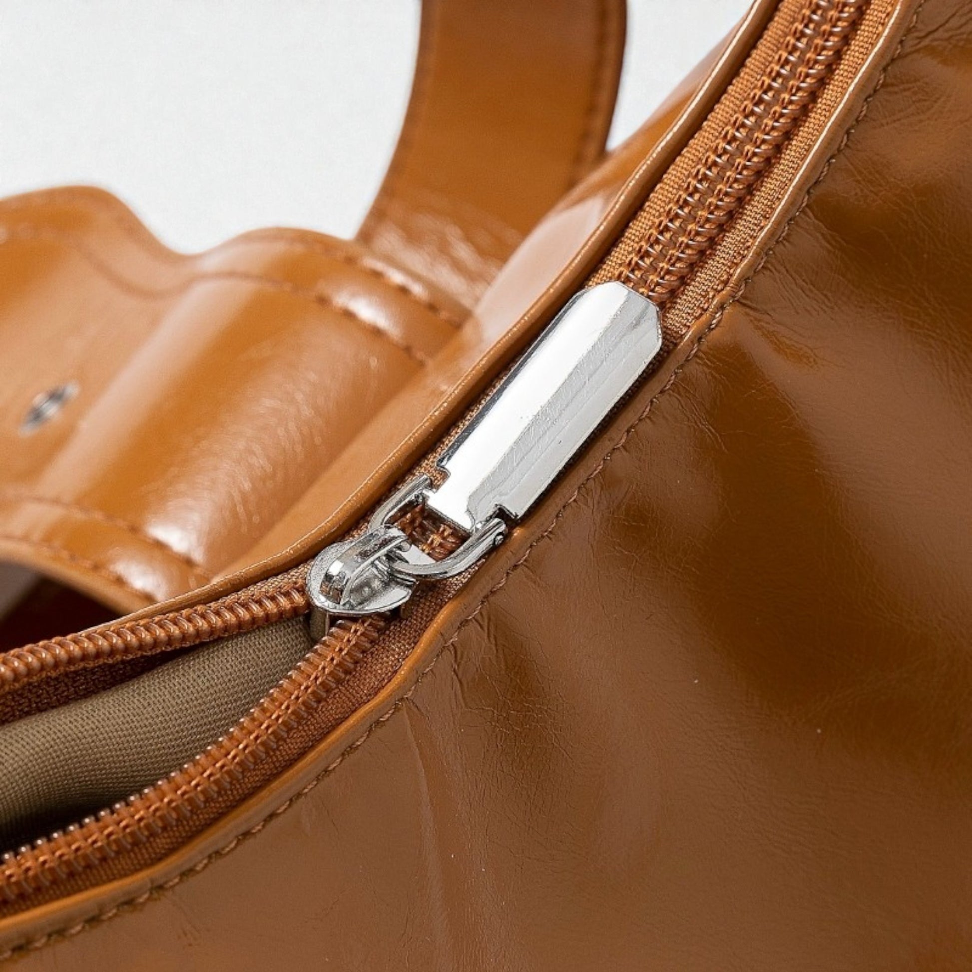 Close-up of a brown leather handbag with a silver zipper.