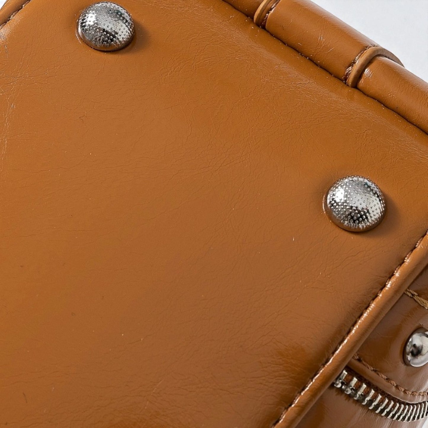 Close-up of a brown leather bag with silver studs and zippers.