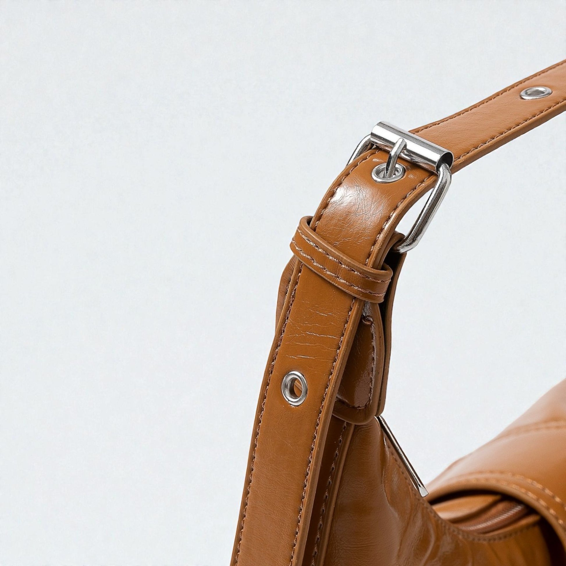 Close-up of a brown leather bag with a silver buckle on a light gray background