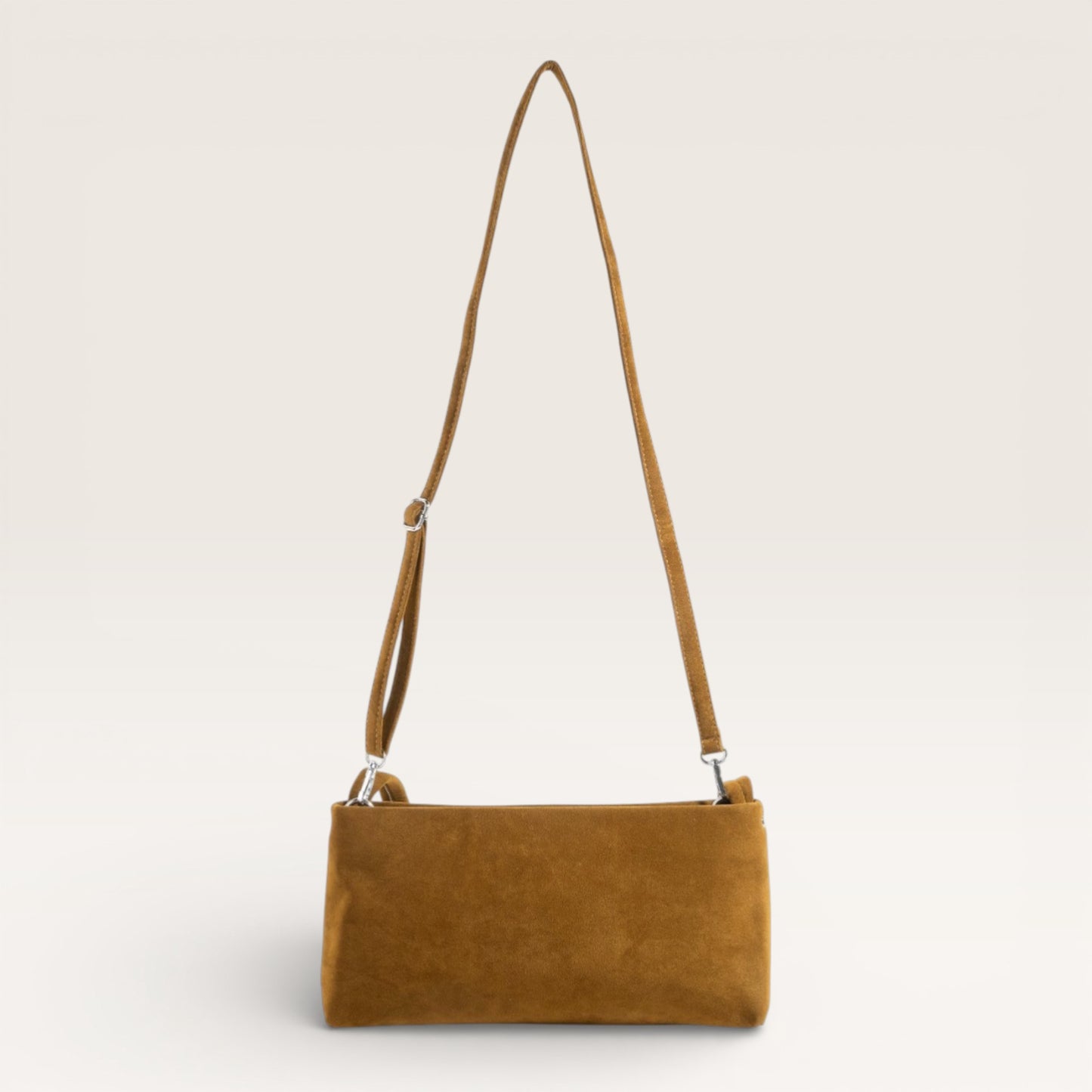 Brown suede handbag with a strap on a light beige background