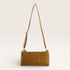 Brown suede handbag with a strap on a light beige background