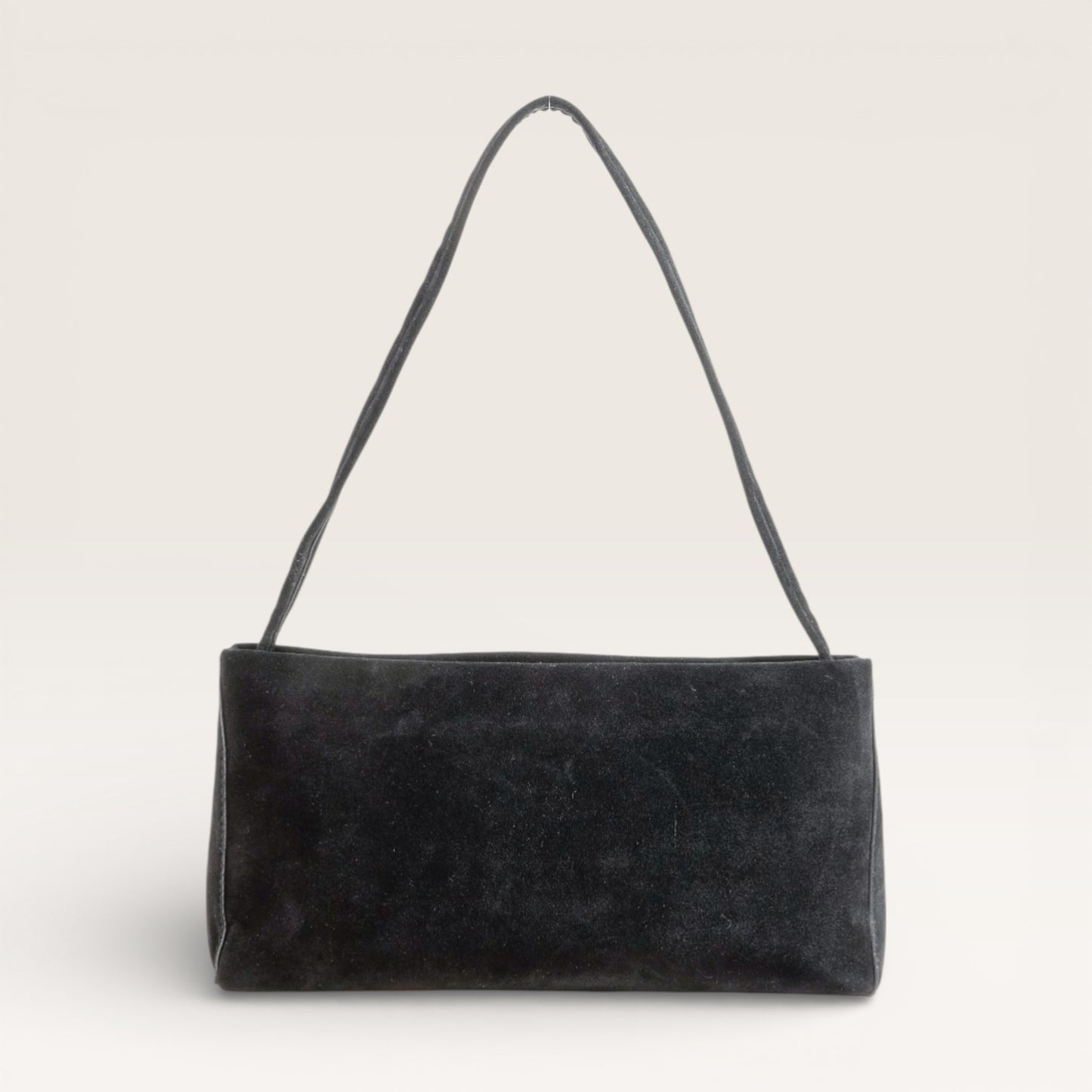 Black suede handbag with a strap on a light gray background