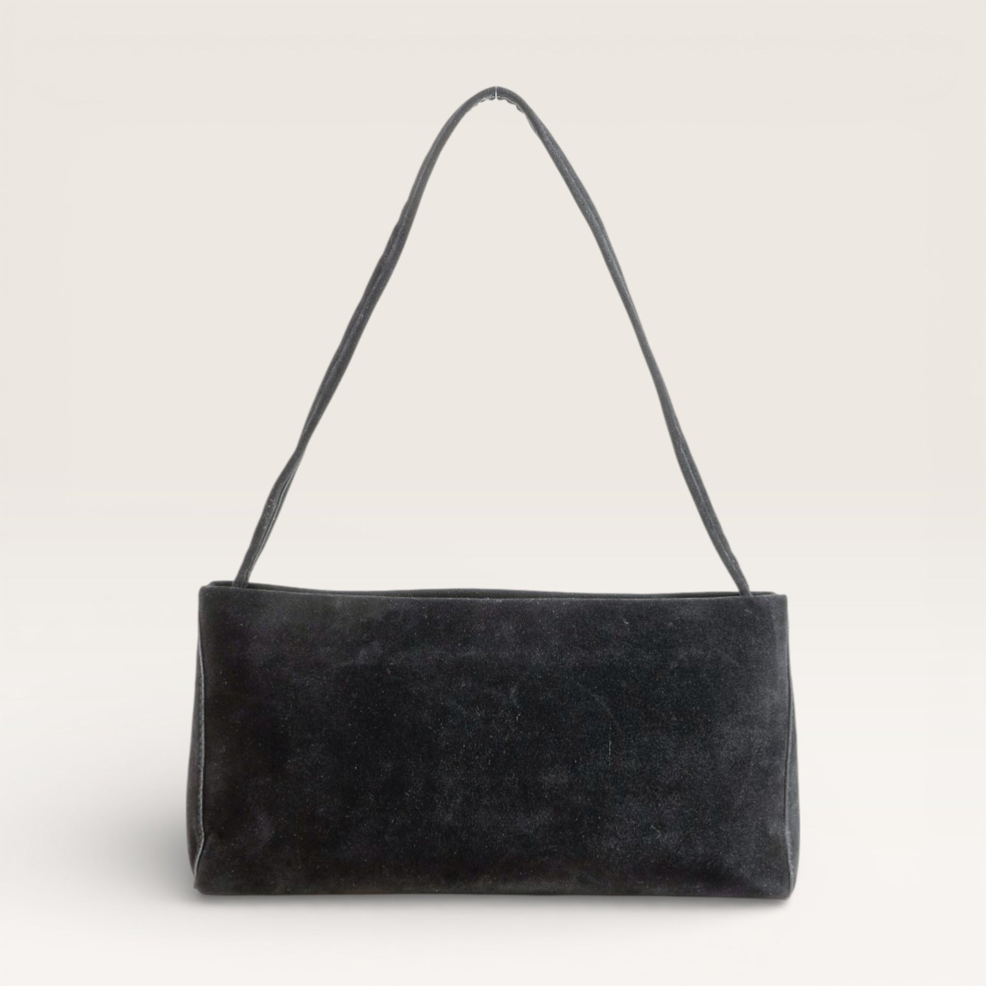 Black suede handbag with a strap on a light gray background