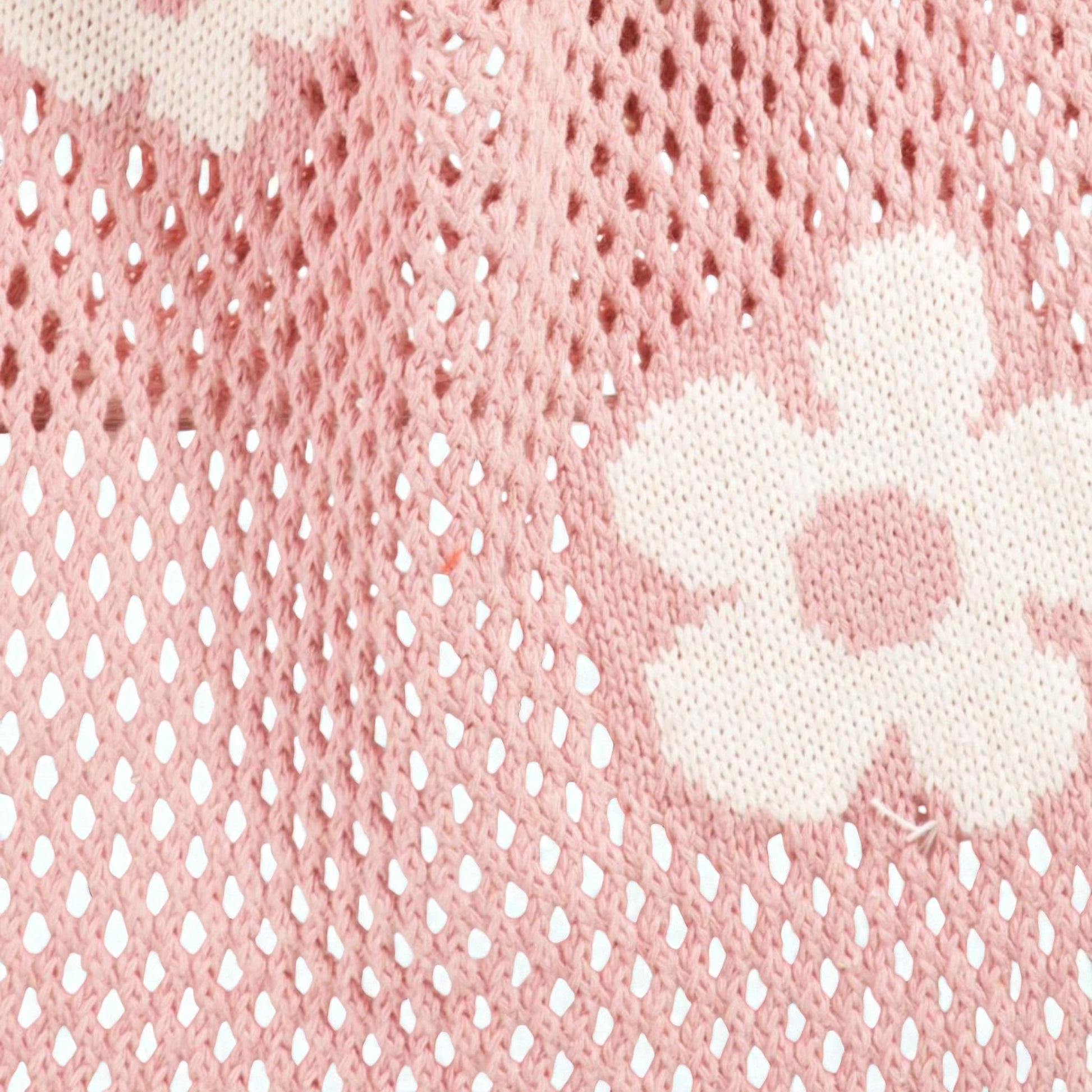 Close-up of pink textured fabric with a white floral design.