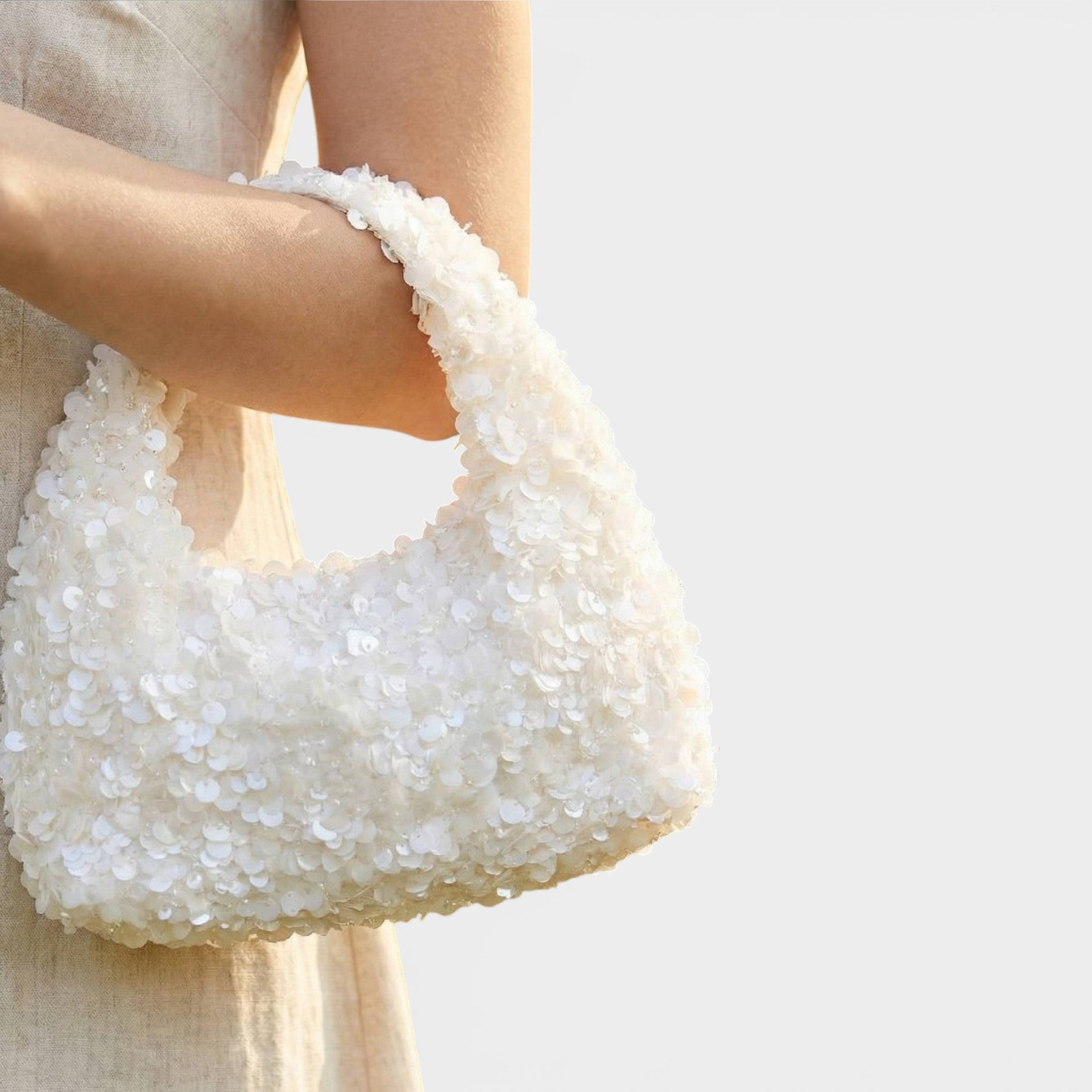 White textured handbag held by a person against a light background