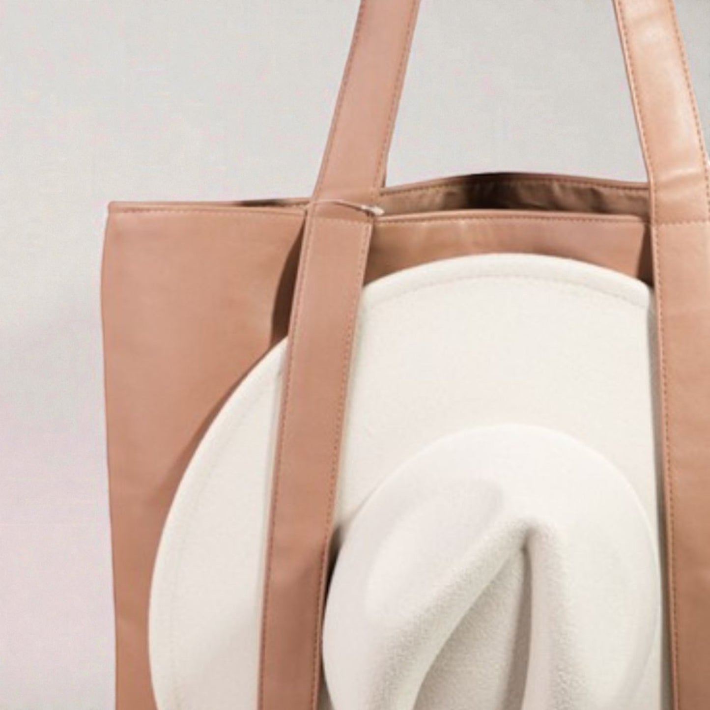 Brown tote bag with a white garment inside on a light gray background