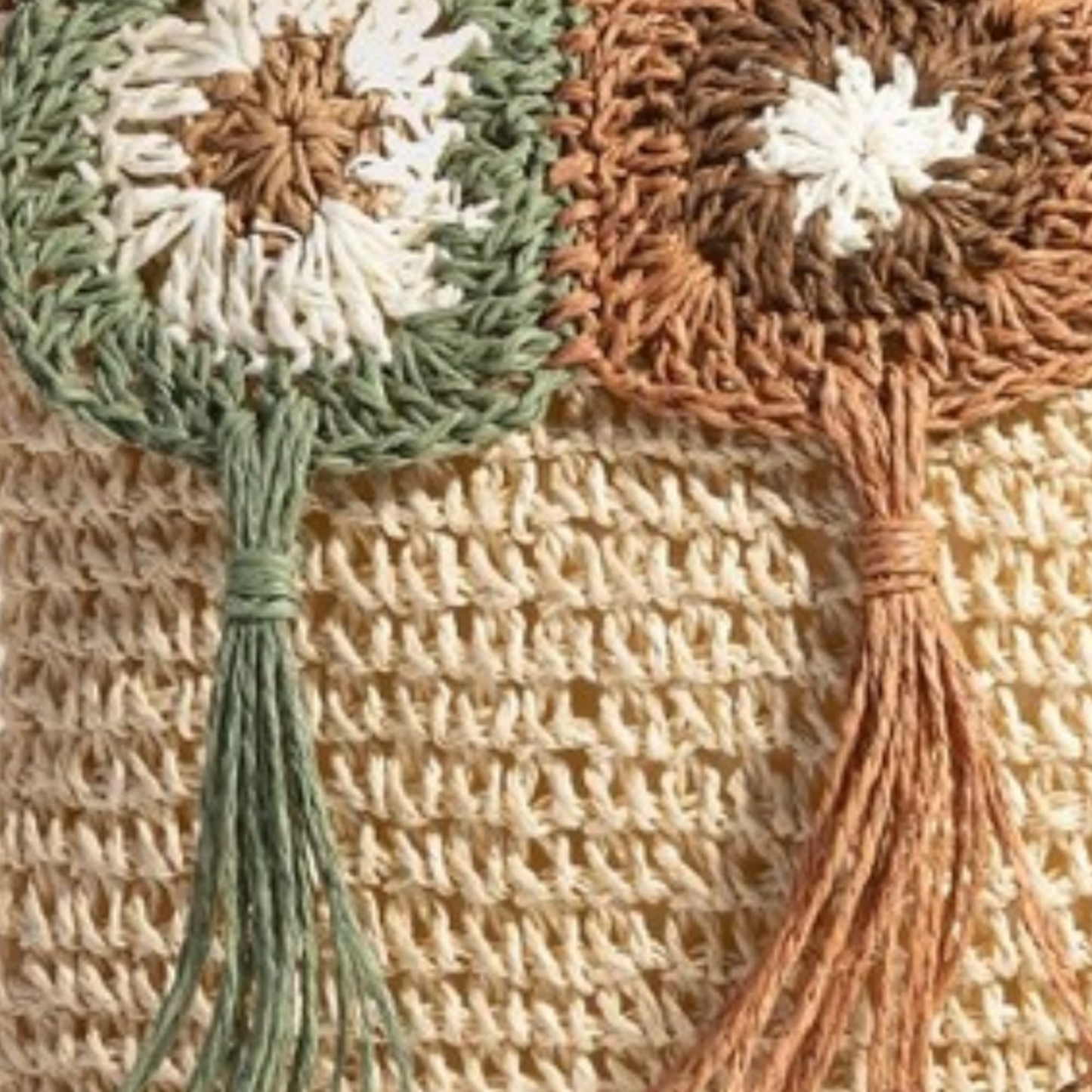 Close-up of a woven bag with floral designs and tassels.