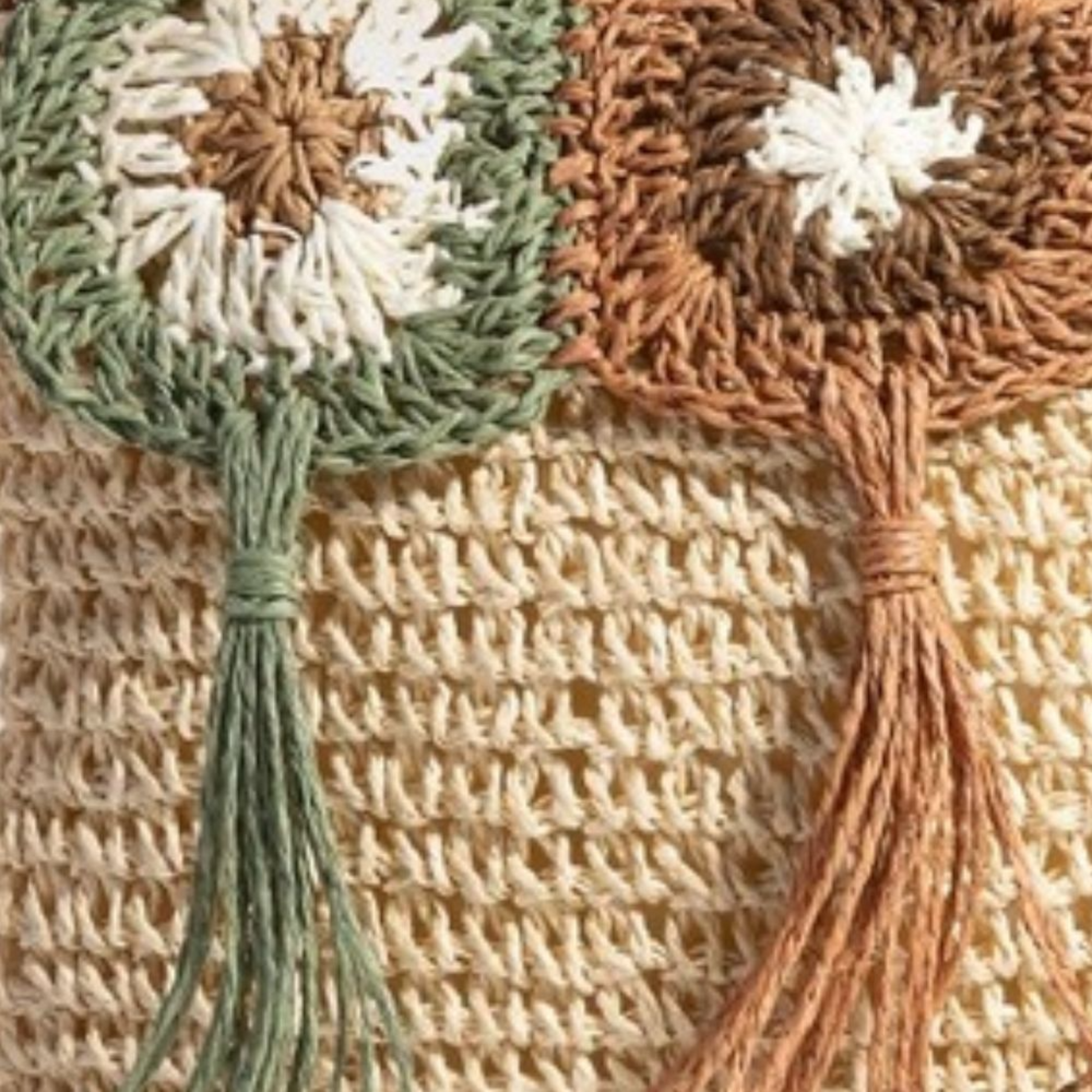 Close-up of a woven bag with floral designs and tassels.