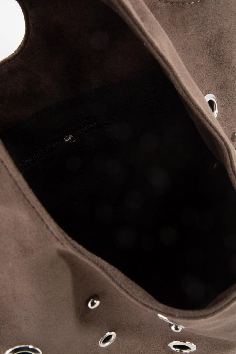 Close-up of a brown leather bag with circular cutouts on a dark background