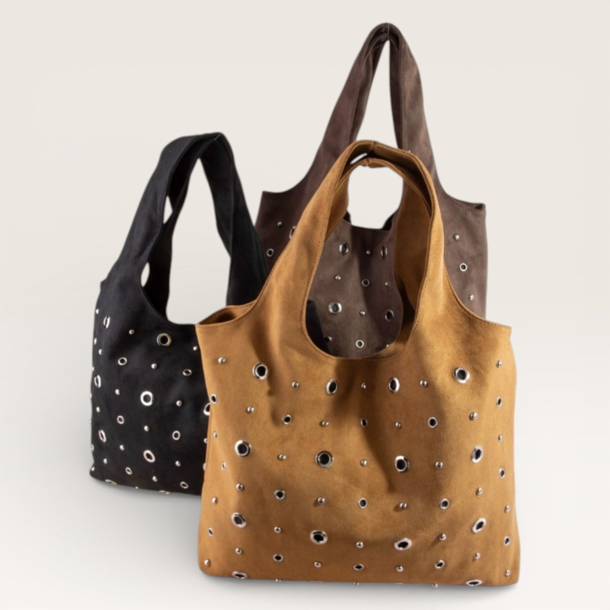 Two handbags, one black and one brown with studs, on a light gray background.