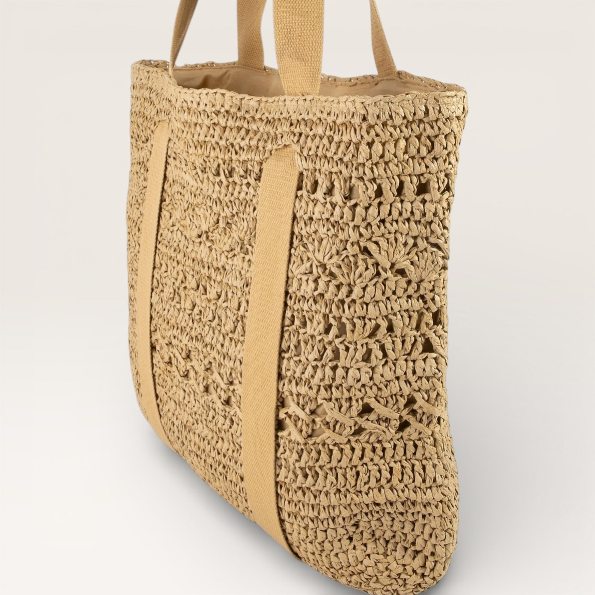 Woven straw tote bag with beige handles on a light gray background