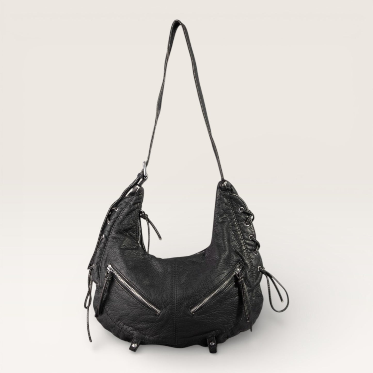 Black leather handbag with zippers on a light gray background