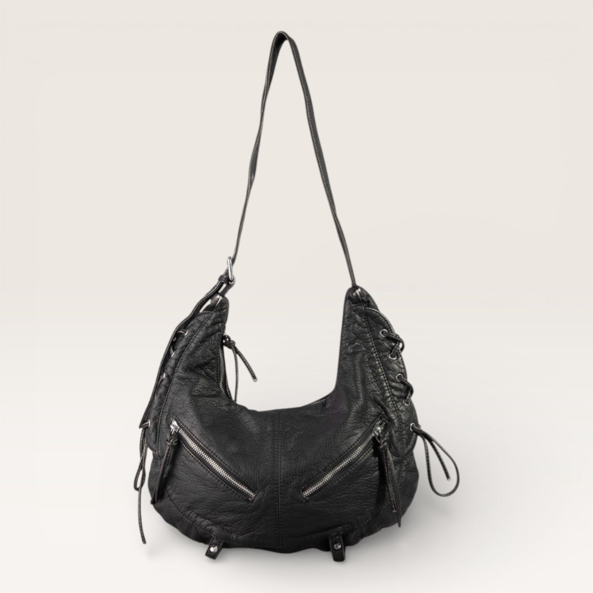 Black leather handbag with zippers on a light gray background