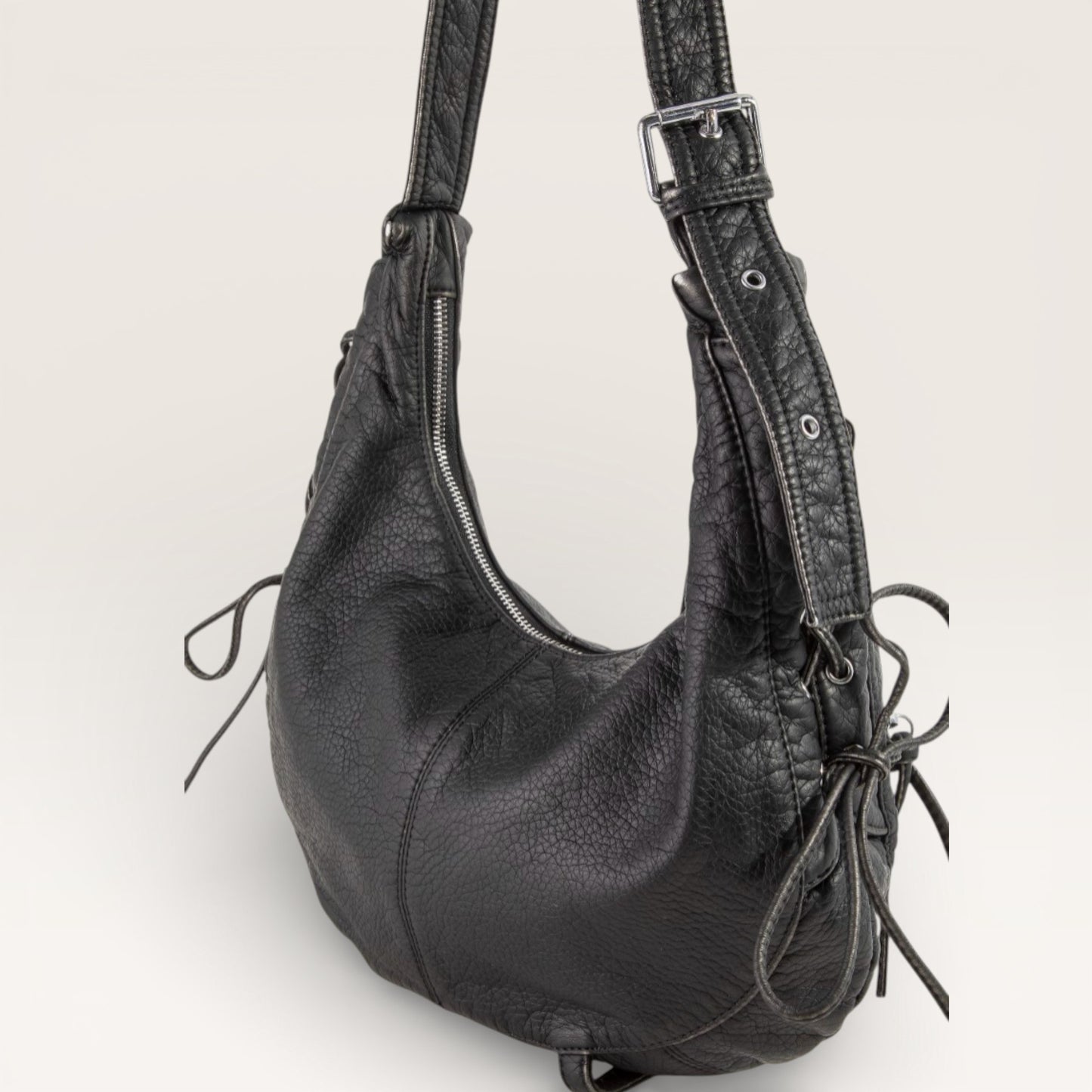 Black leather handbag with a strap on a light gray background