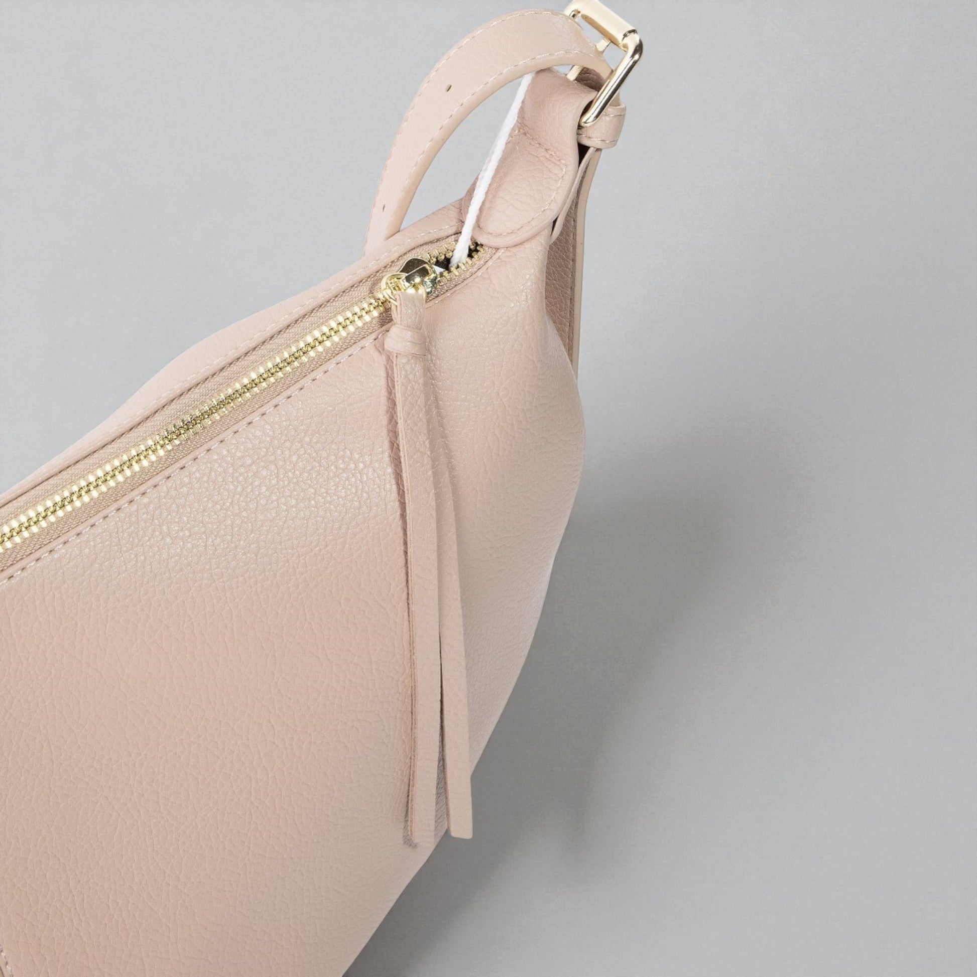 Beige handbag with gold zipper on a light gray background