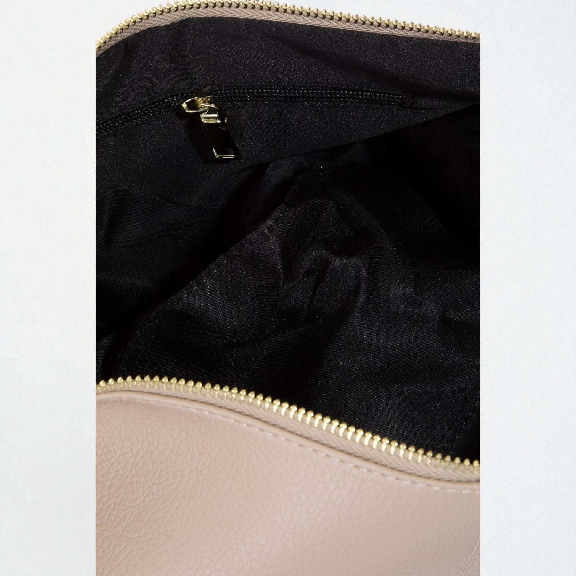Close-up of a beige handbag with a gold zipper, showing the interior.
