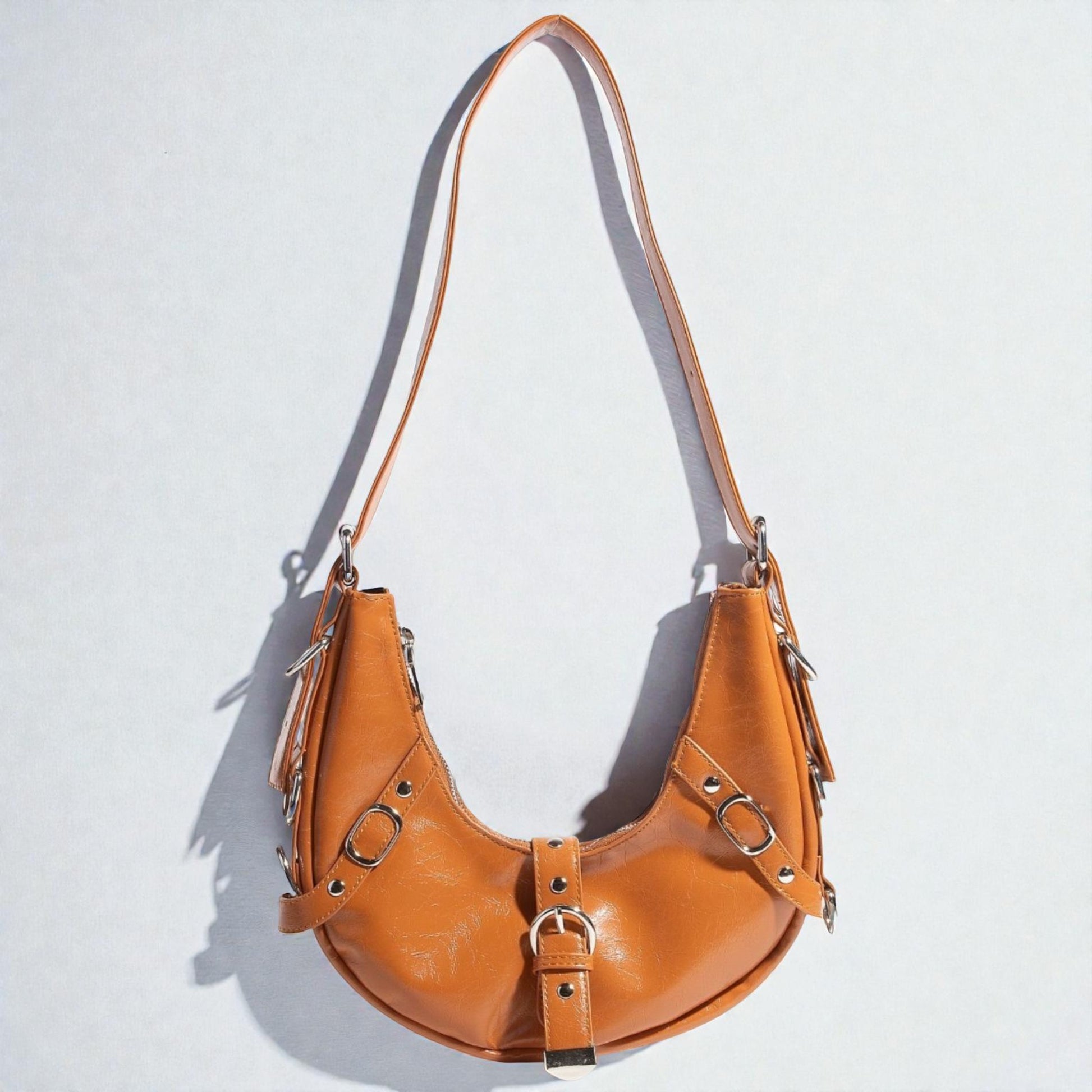 Brown leather handbag with metal accents on a light gray background