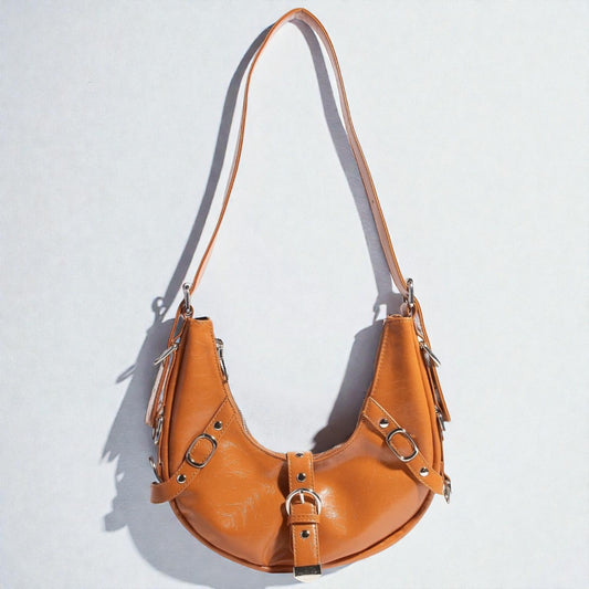 Brown leather handbag with metal accents on a light gray background