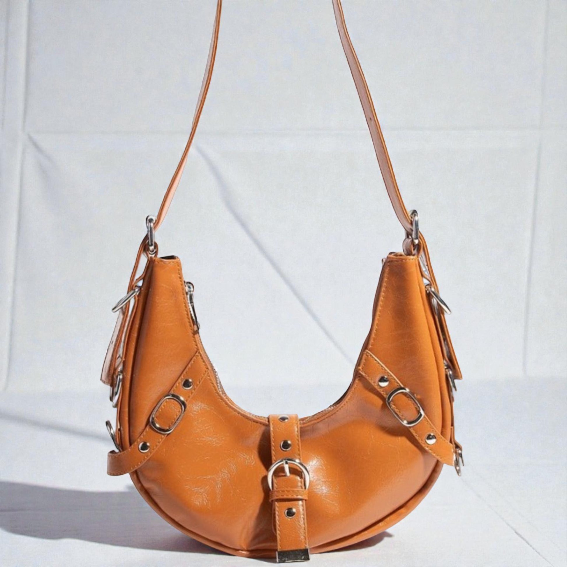 Brown leather handbag with silver buckles on a white background