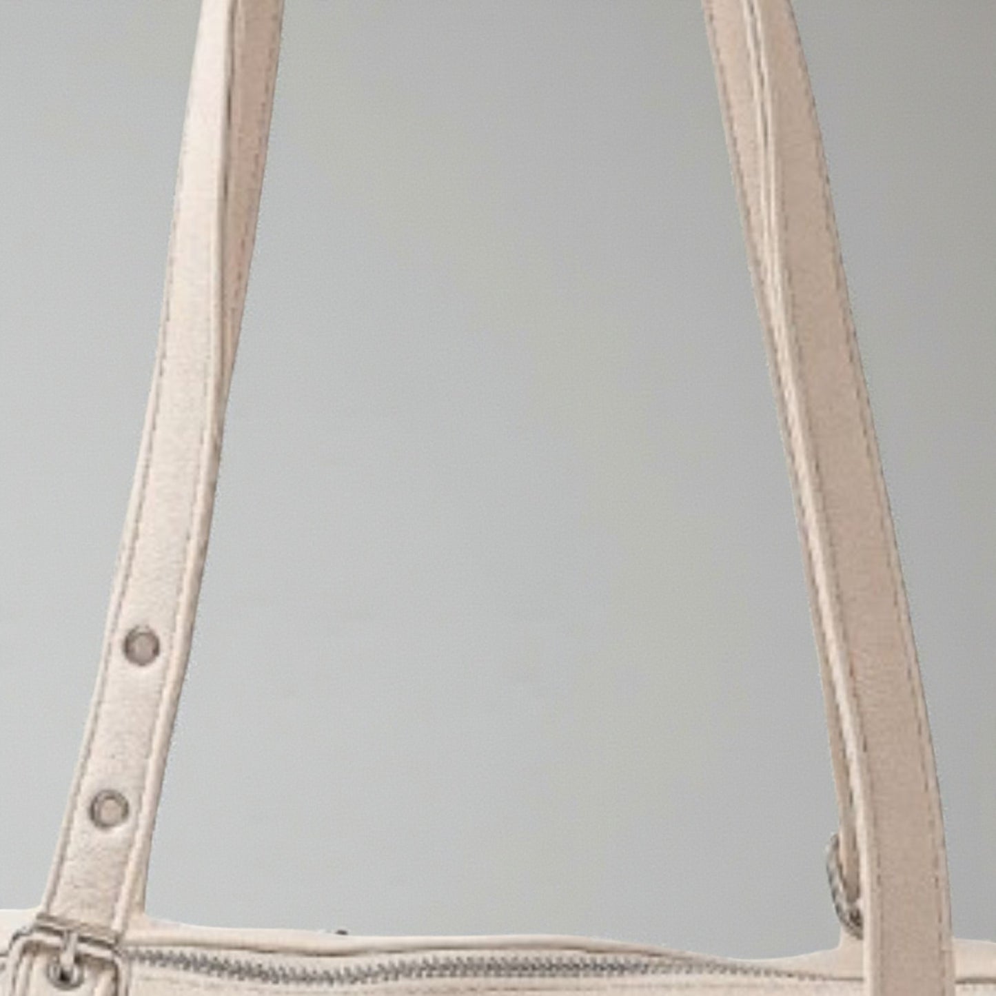 Close-up of beige handbag handles on a gray background