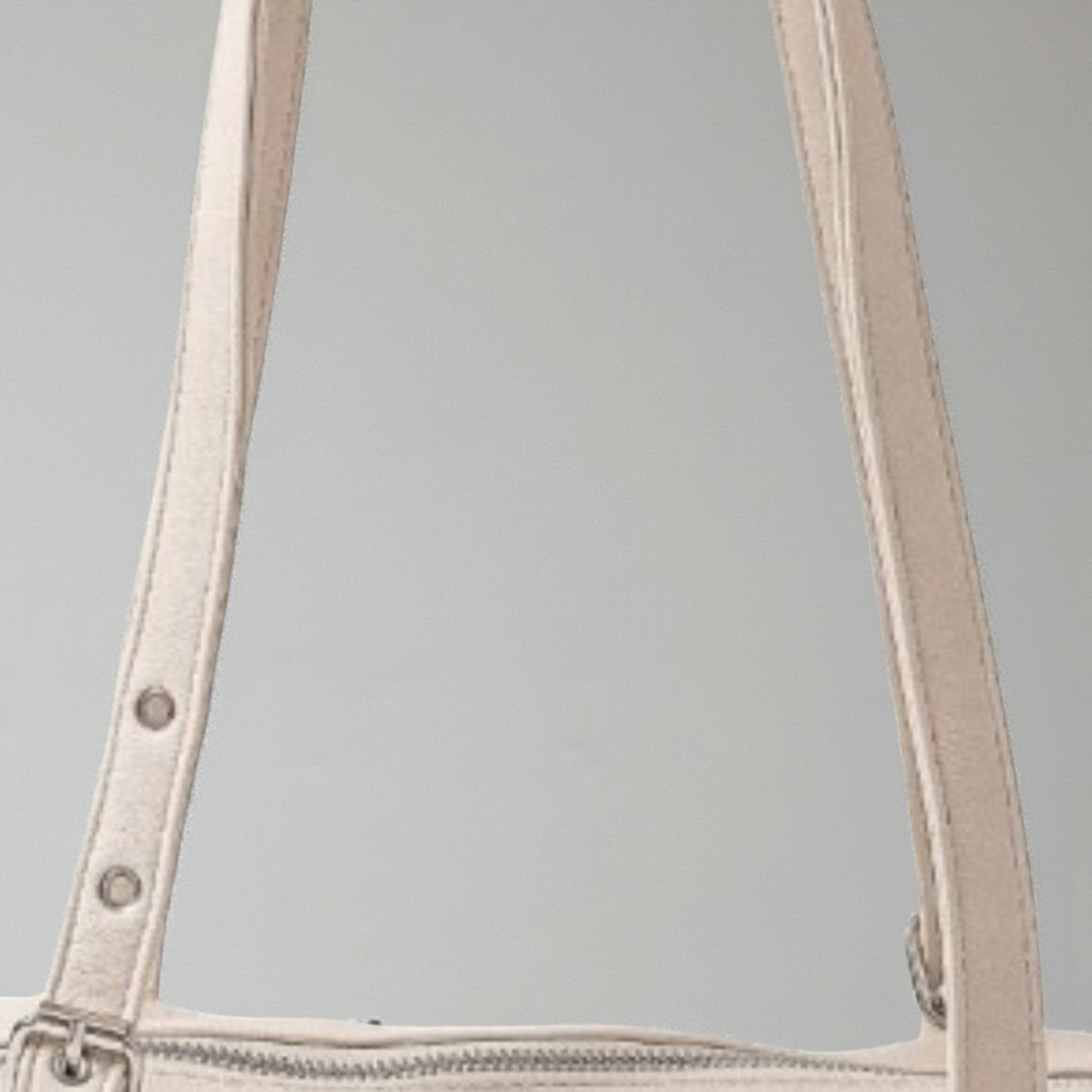 Close-up of beige handbag handles on a gray background